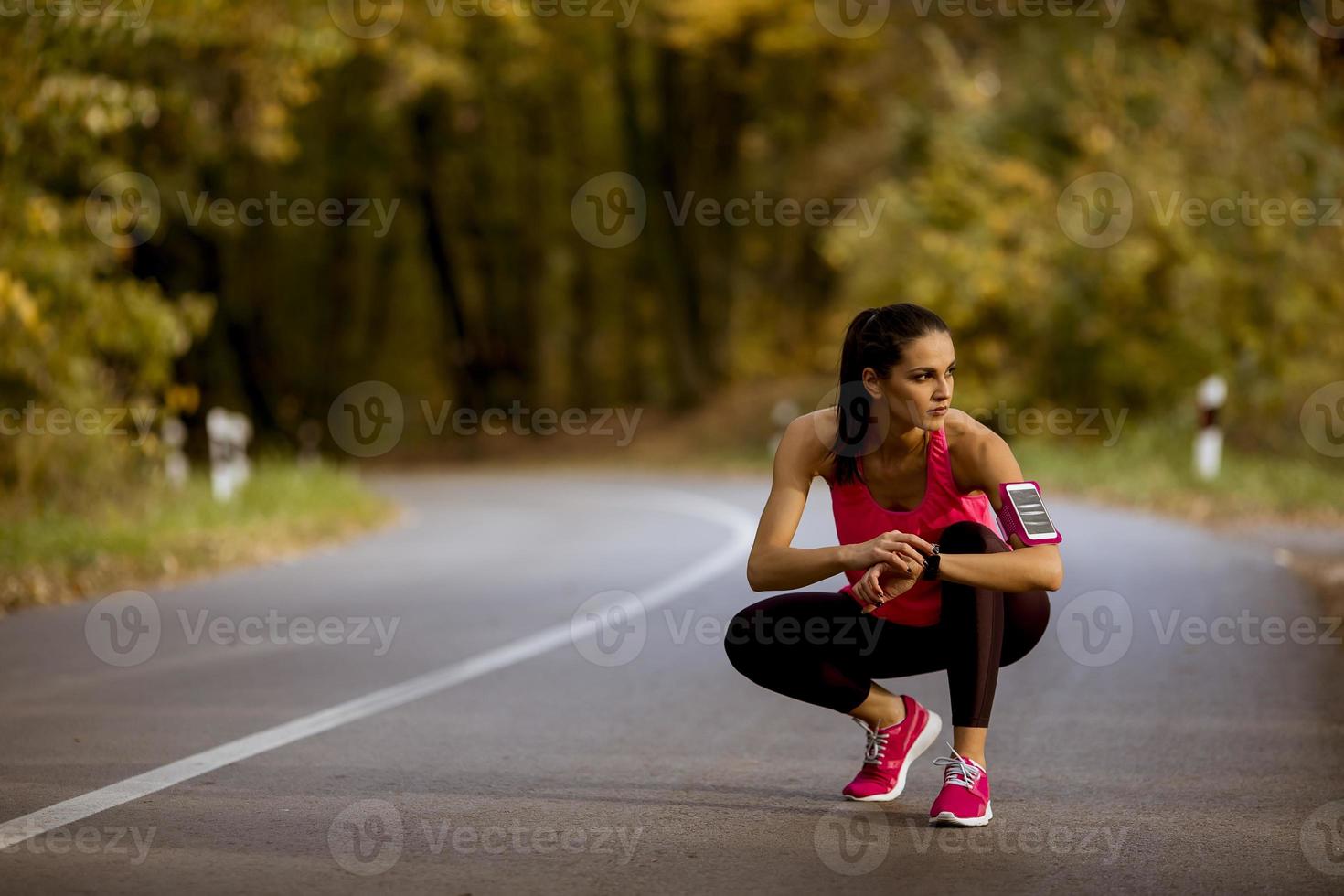 junge Frau macht Pause beim Training im Herbstwald foto
