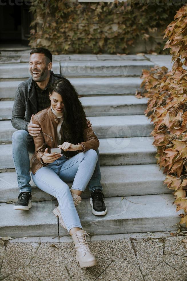 junges Paar sitzt an einem Herbsttag auf Außentreppen foto