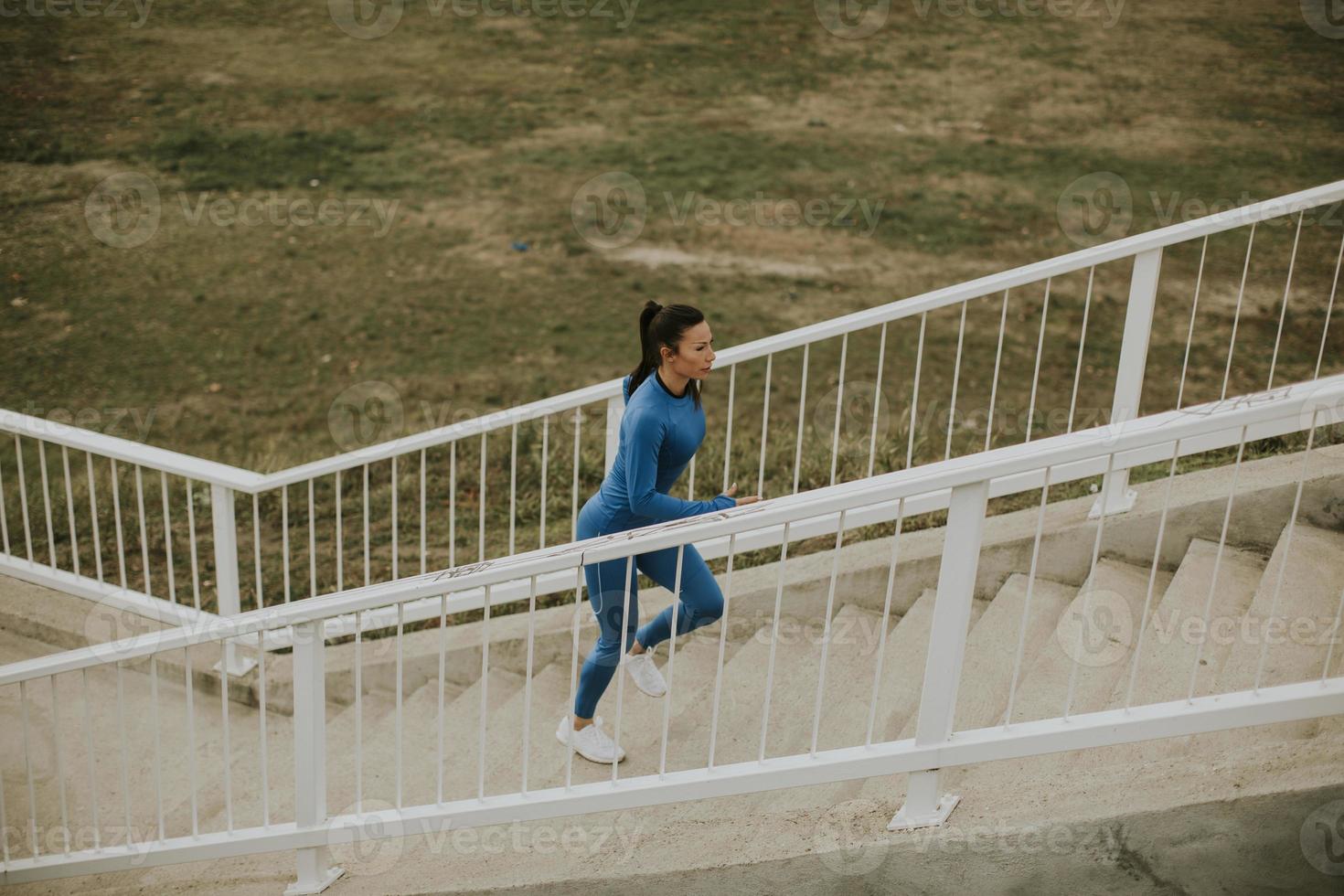 junge Frau im blauen Trainingsanzug läuft am Herbstmorgen auf der Außentreppe foto