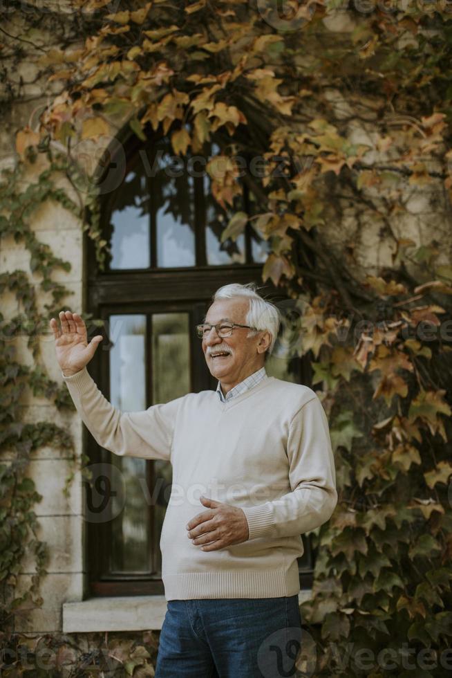 älterer Mann, der am Herbsttag am Fenster steht foto