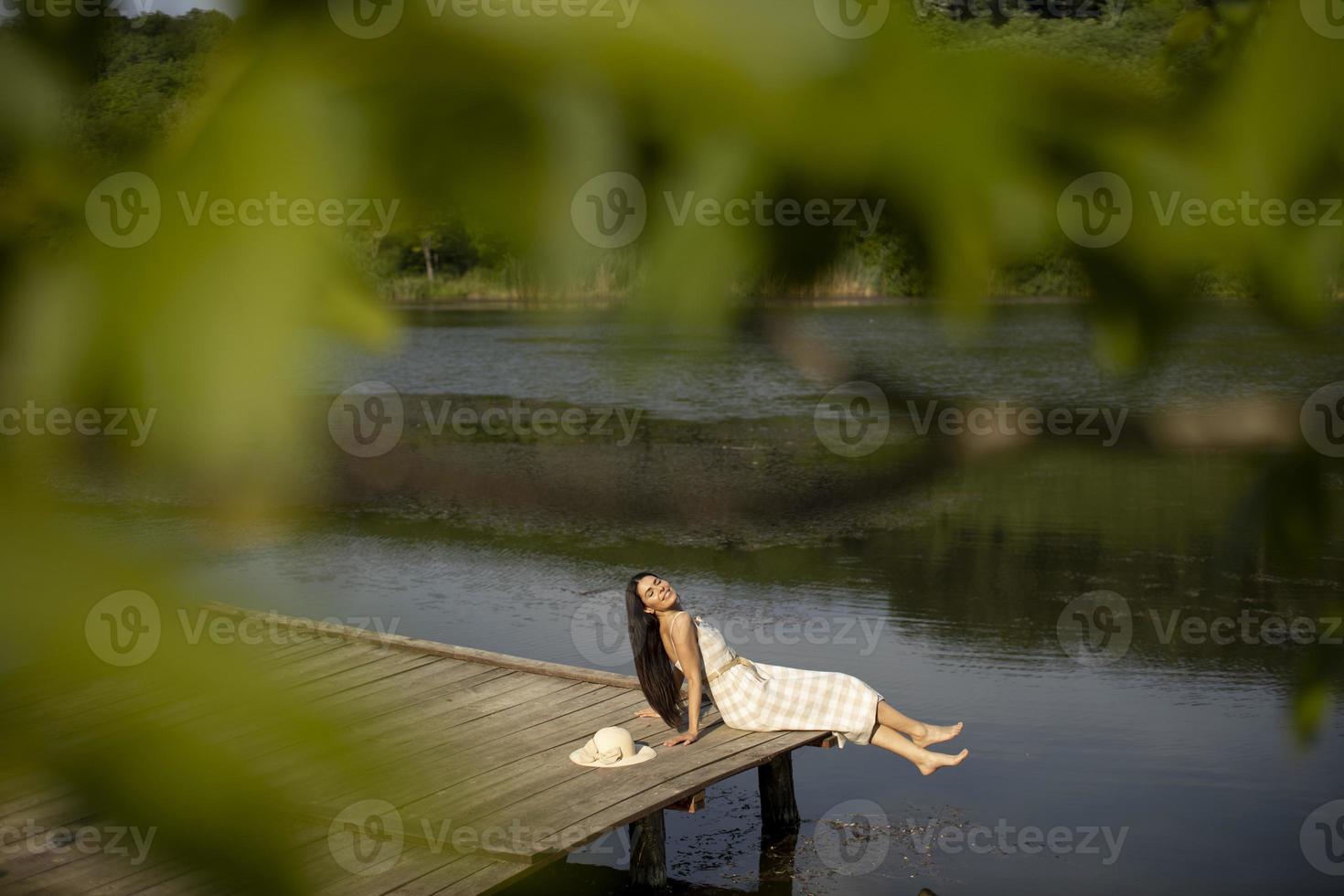 entspannende junge Frau auf Holzsteg am See foto