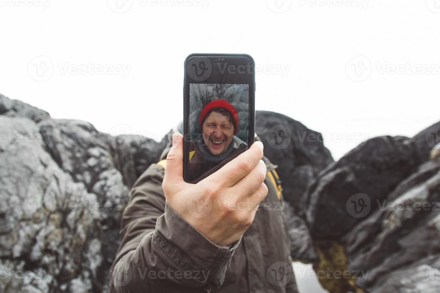 Reisender, der ein Selbstporträt mit einem Smartphone vor dem Hintergrund von Bergen und Felsen macht. Platz für Text oder Werbung foto