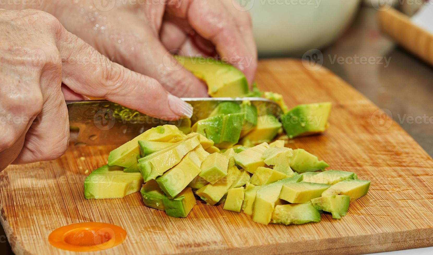 Cook schneidet reife Avocado in Scheiben für die Salatzubereitung foto