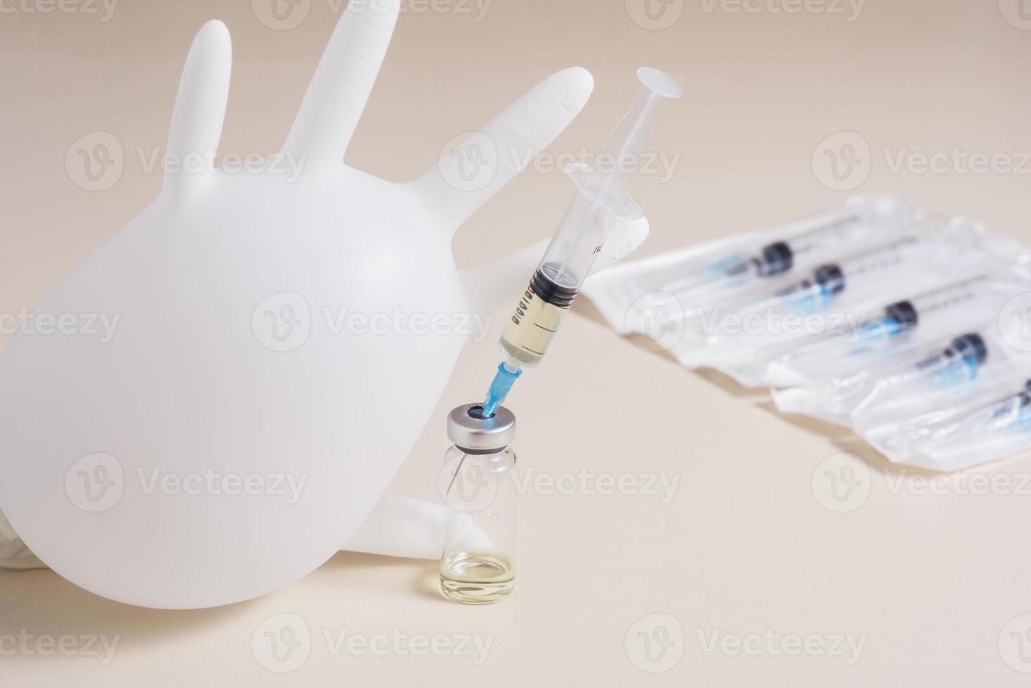 Massenimpfung gegen das Coronavirus. Aufgeblasener medizinischer Handschuh neben einer Spritze mit einem Covid-19-Impfstoff. foto