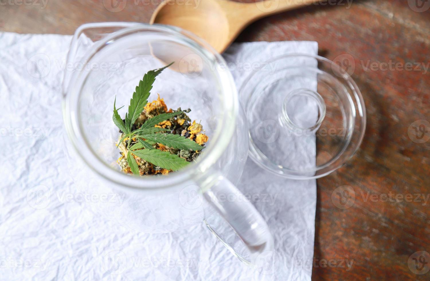 Cannabisblatt mit Blütentee im Glas für gesundes Aromatrinken foto