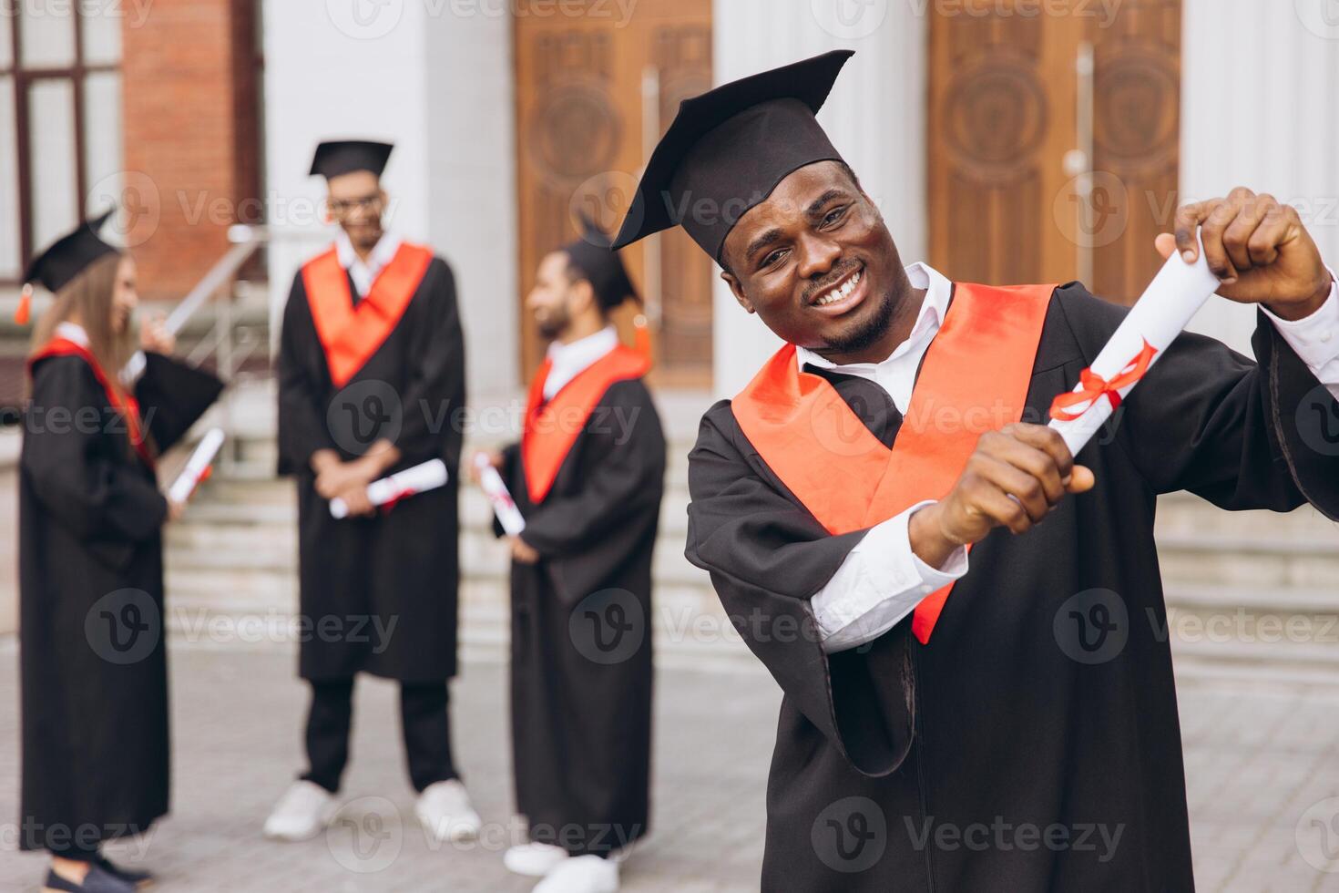 glücklich afrikanisch amerikanisch männlich Absolventen feiern halten Diplome im Deckel und Kleid beim Universität Zeremonie foto