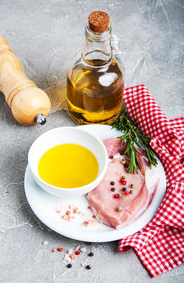 frische rohe Schweinekoteletts mit Gewürzen und Kräutern foto