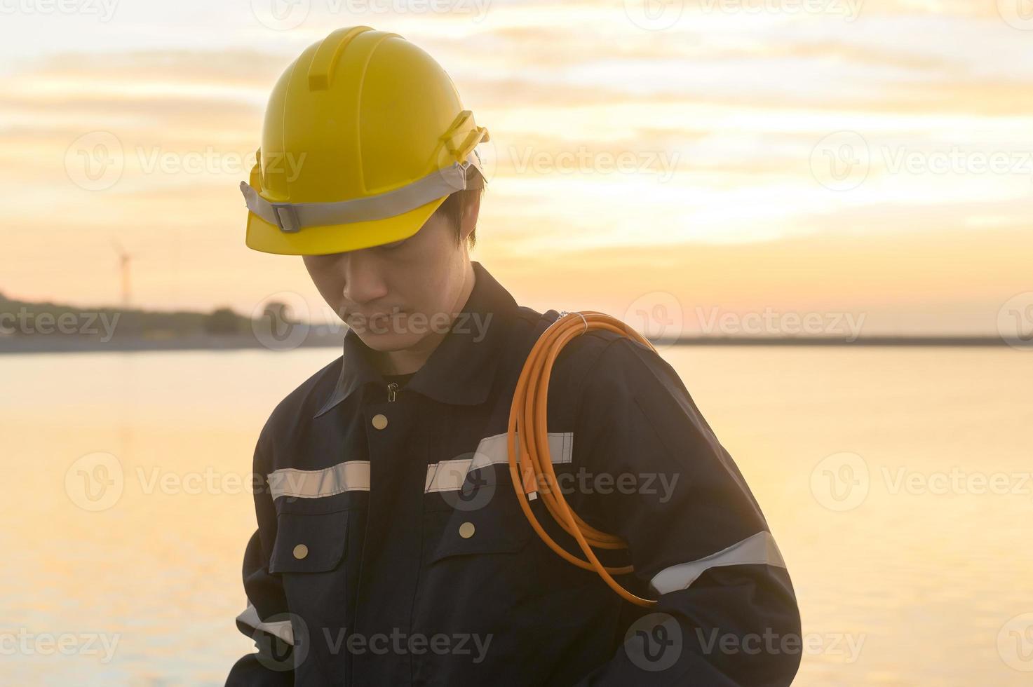 ein männlicher Ingenieur, der bei Sonnenuntergang einen Schutzhelm trägt. foto