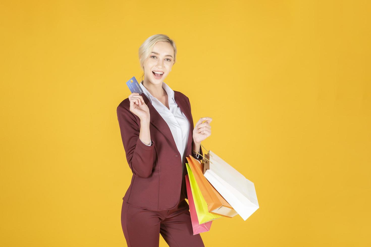 Geschäftsfrau ist glücklich mit dem Einkaufen im gelben Hintergrund des Studios foto