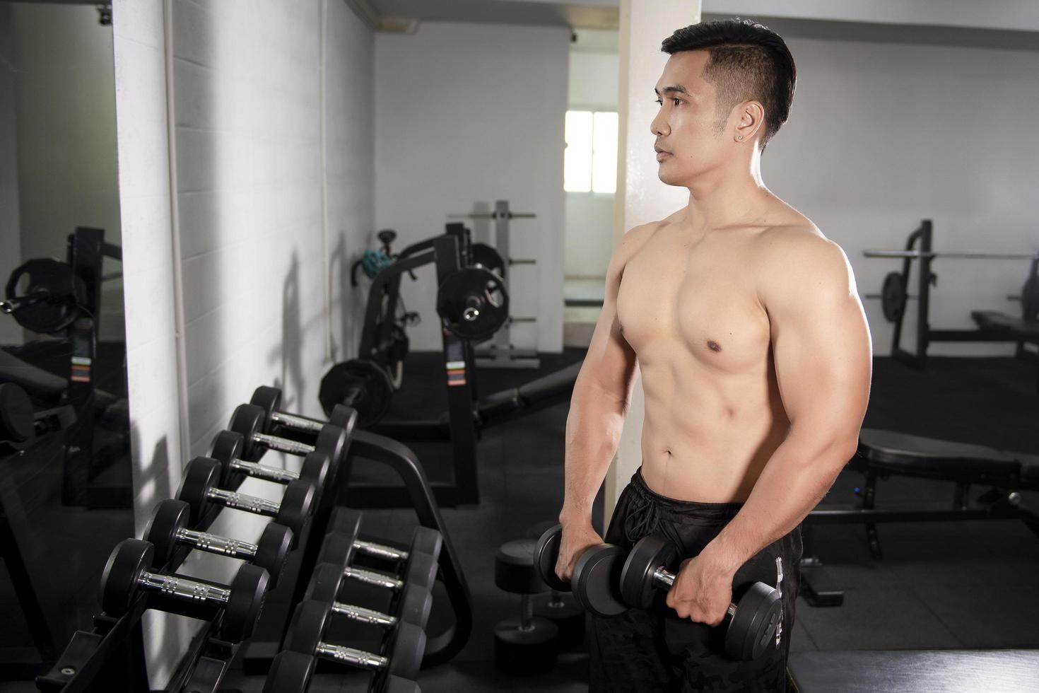 muskulöser Fitness-Mann-Bodybuilder trainiert mit Hanteln im Fitnessstudio foto