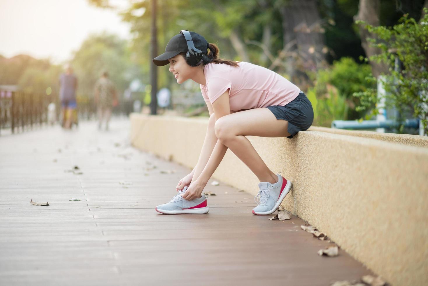 Schöne Frau hört Musik und bindet Schuhe im Park foto