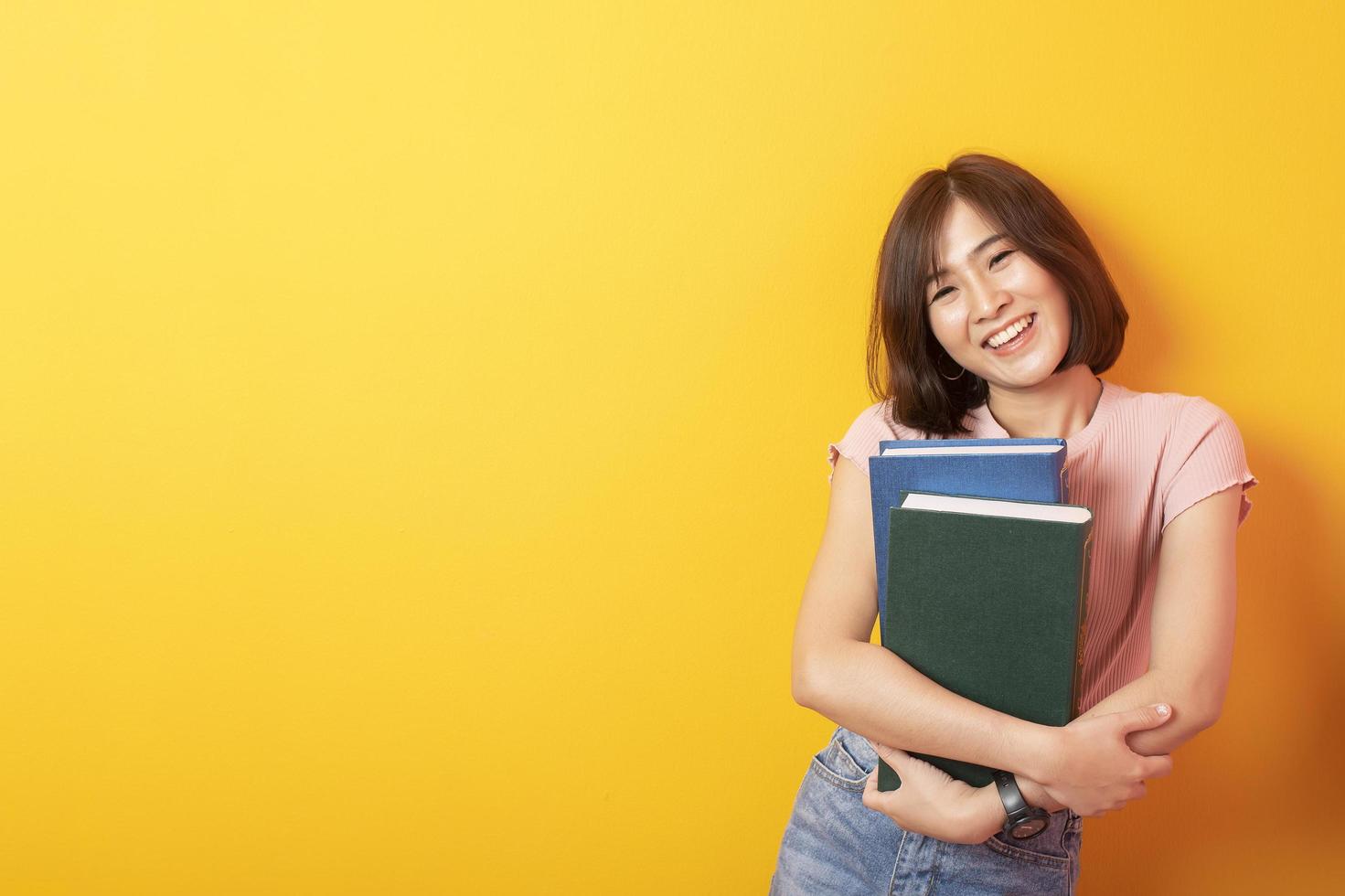 schöne asiatische Studentin glücklich auf gelbem Hintergrund foto