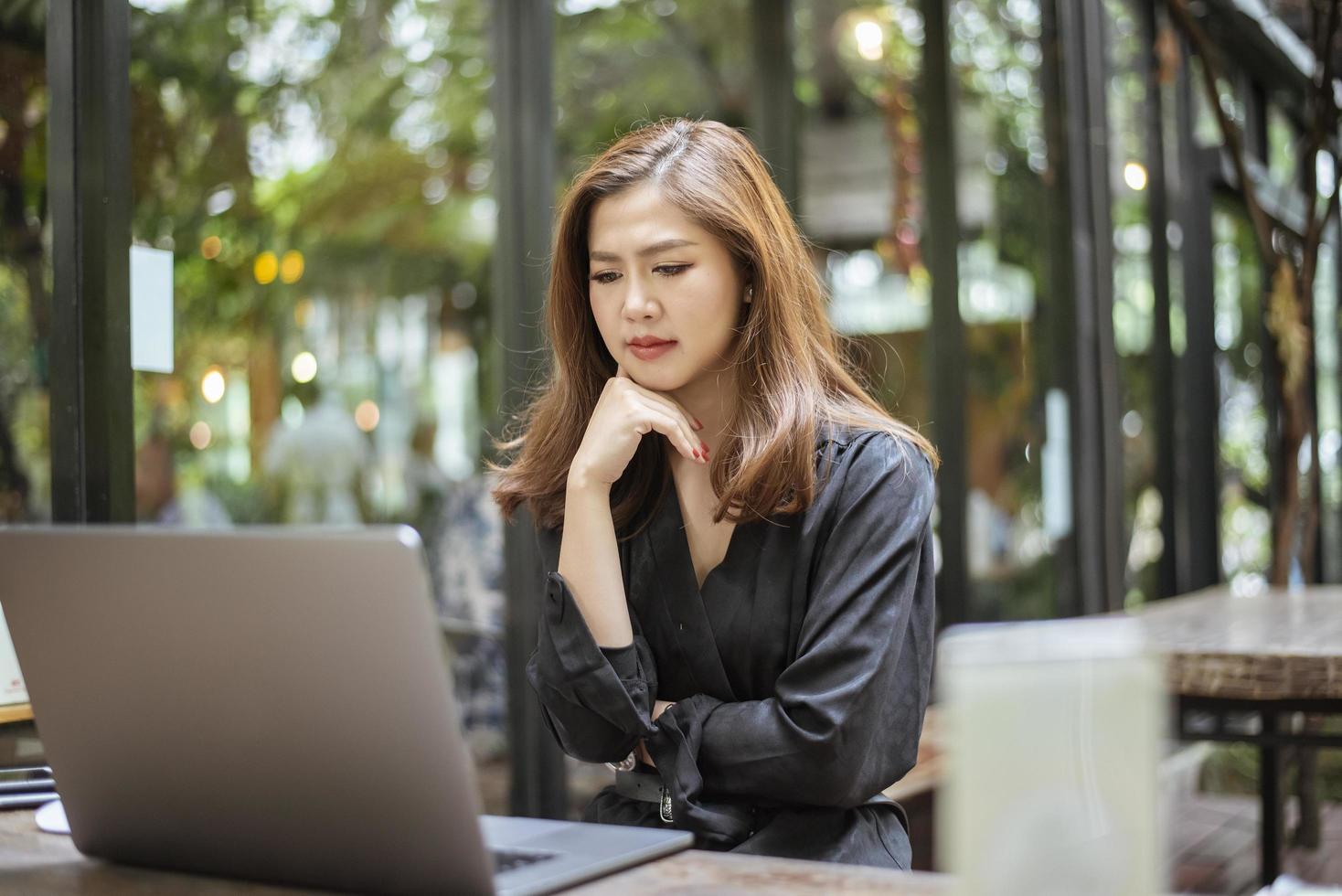 gestresste asiatische frau, die kopfschmerzen im café-shop verspürt foto