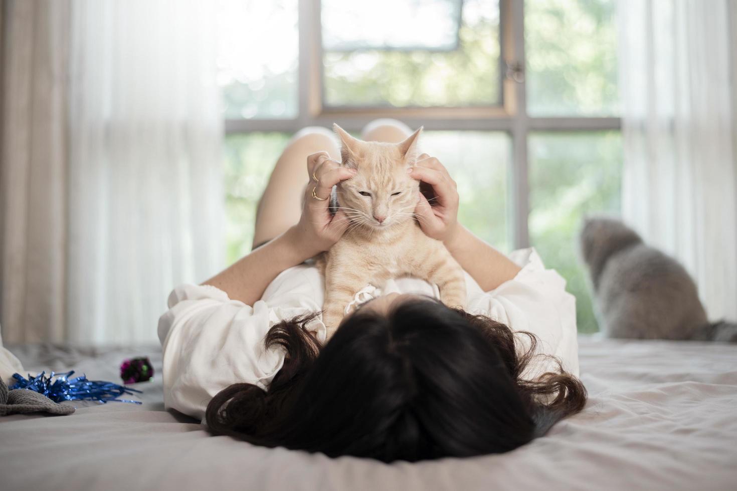 schöne asiatische katzenliebhaberin spielt mit katze in ihrem zimmer foto