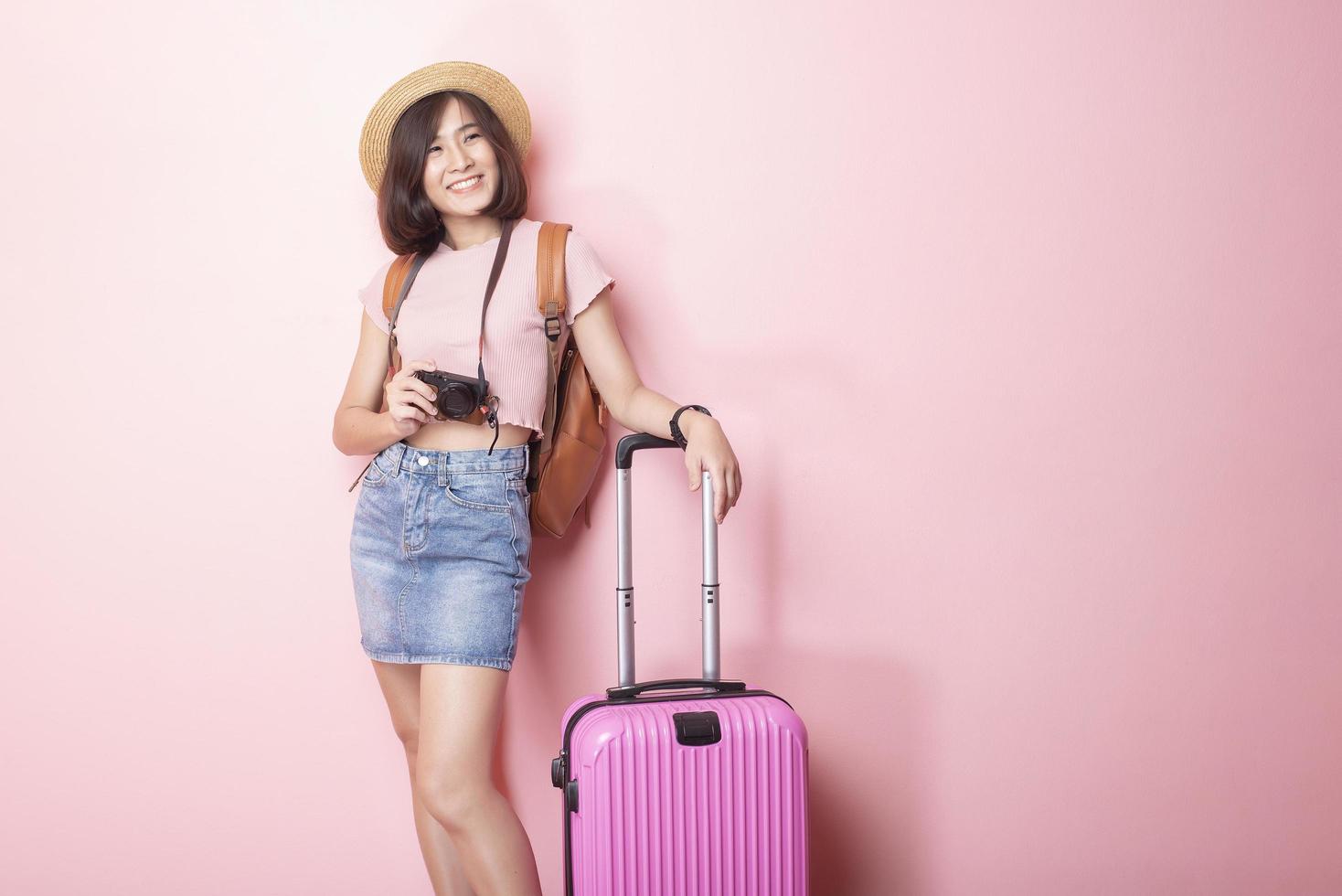 glückliche asiatische Touristin auf rosa Hintergrund foto