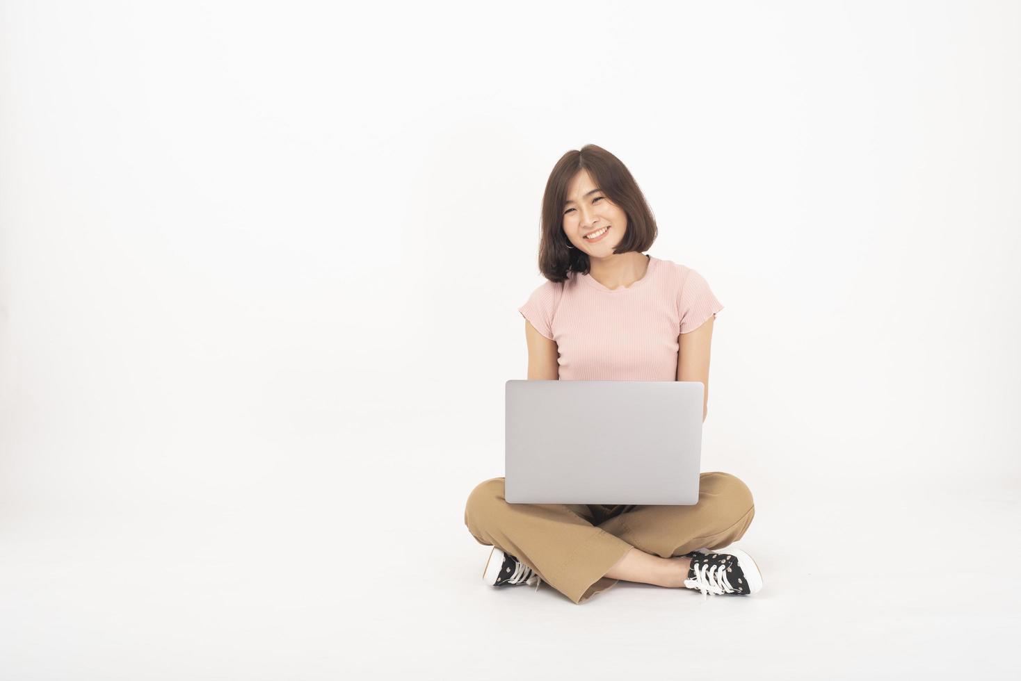 Süße asiatische Teenager-Frau arbeitet mit Computer auf weißem Hintergrund foto