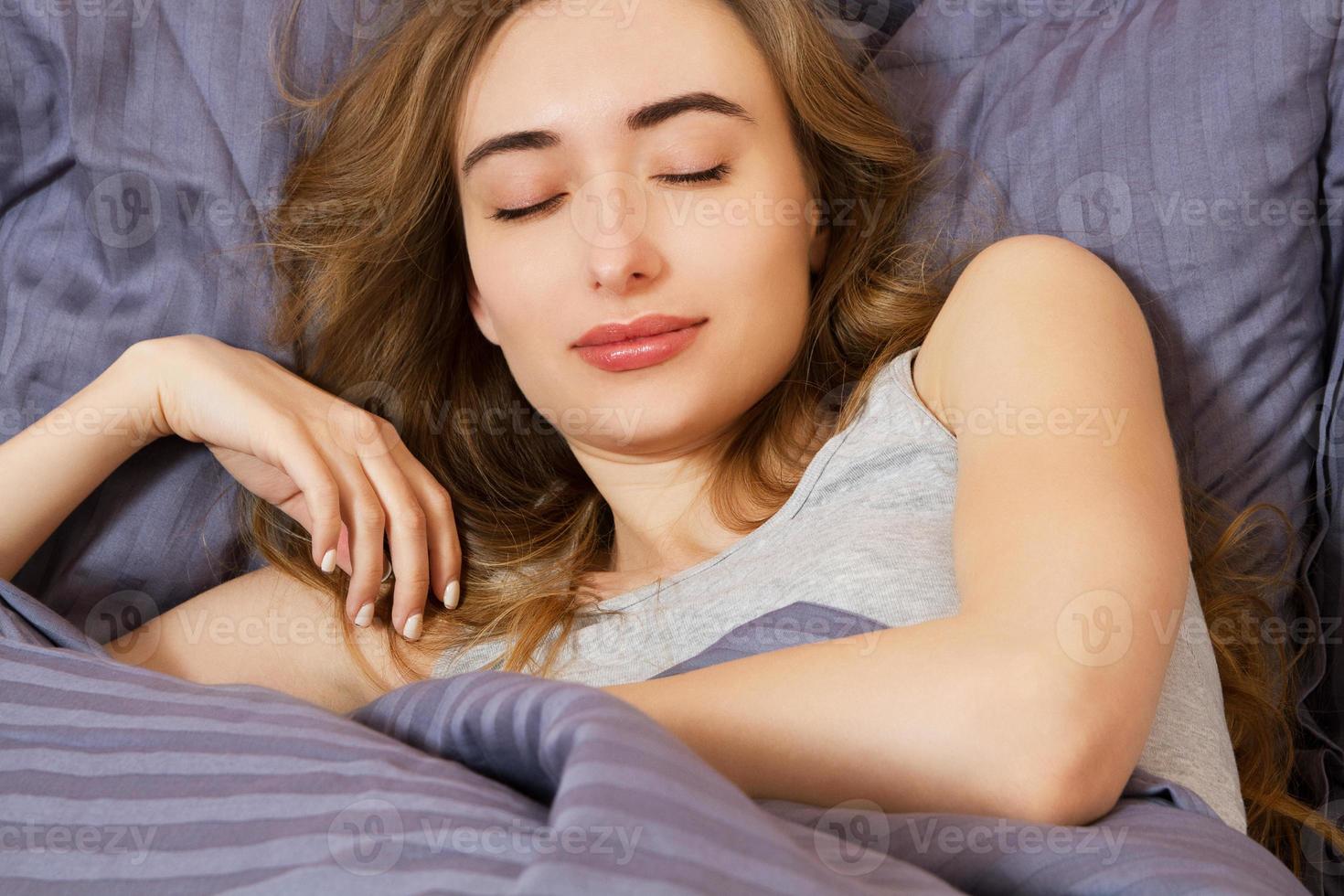 attraktive junge Lächelnfrau, die im Schlafzimmer schläft. gesunder Lebensstil. Wellnesskonzept foto