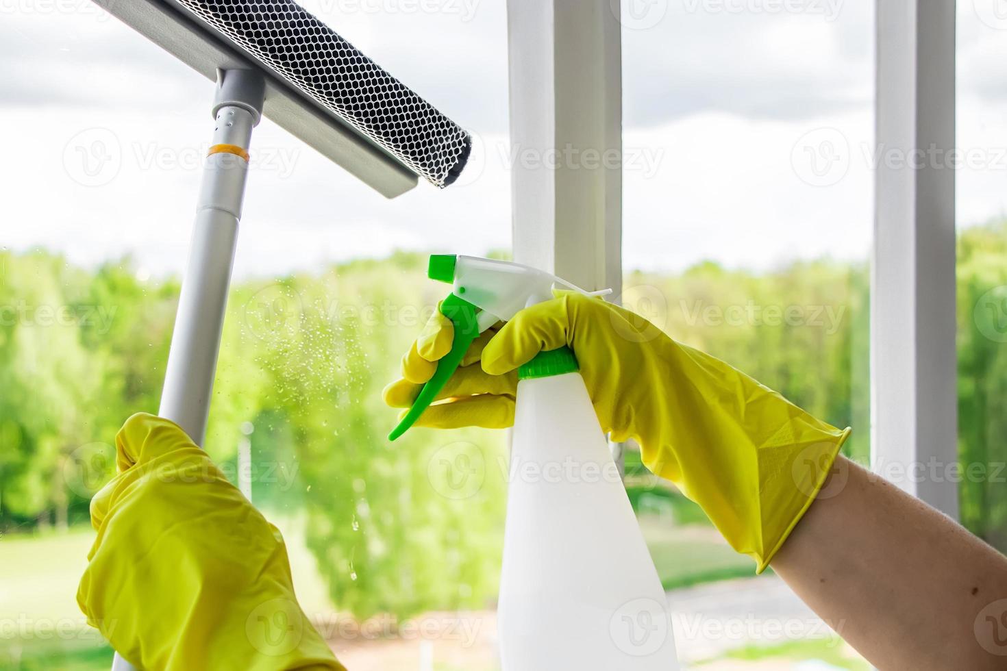 Frau in gelben Gummihandschuhen wischt das Glas ab. foto