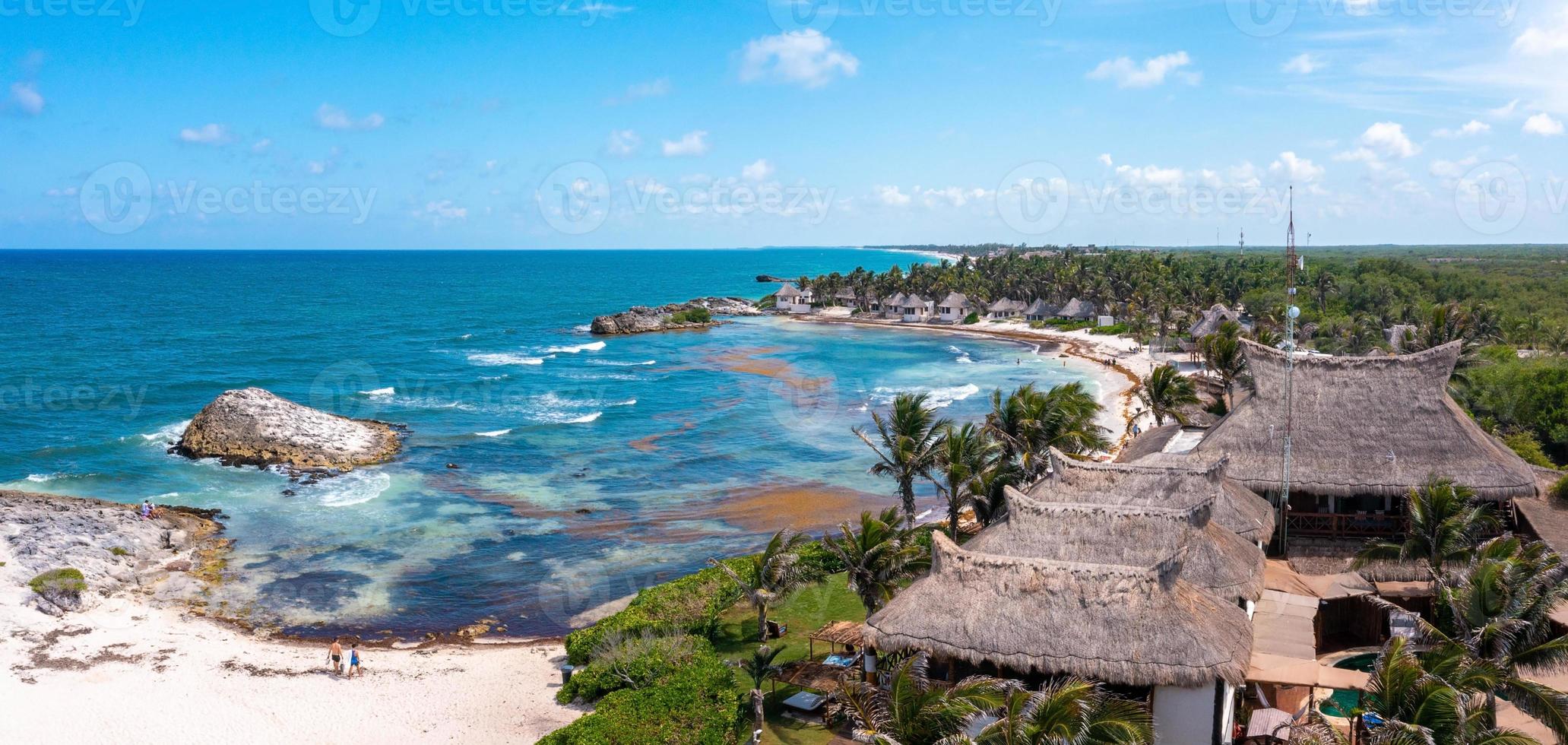 luftige küste von tulum am strand mit einem magischen karibischen meer und kleinen hütten an der küste. foto