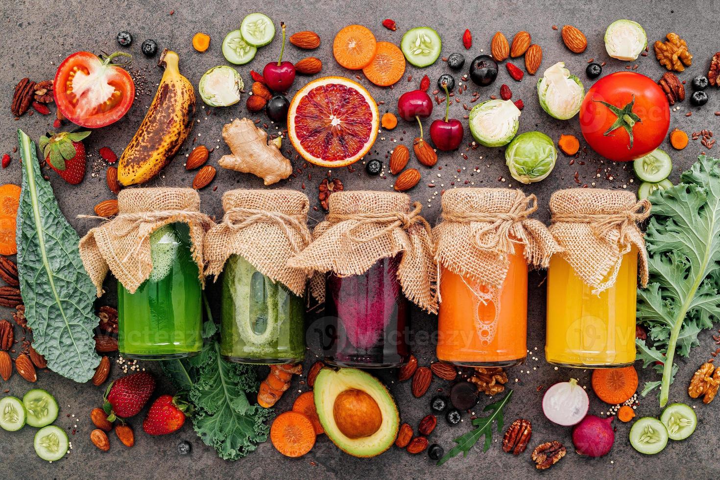 Bunte gesunde Smoothies und Säfte in Flaschen mit frischen tropischen Früchten und Superfoods auf dunklem Steinhintergrund mit Kopierraum. foto