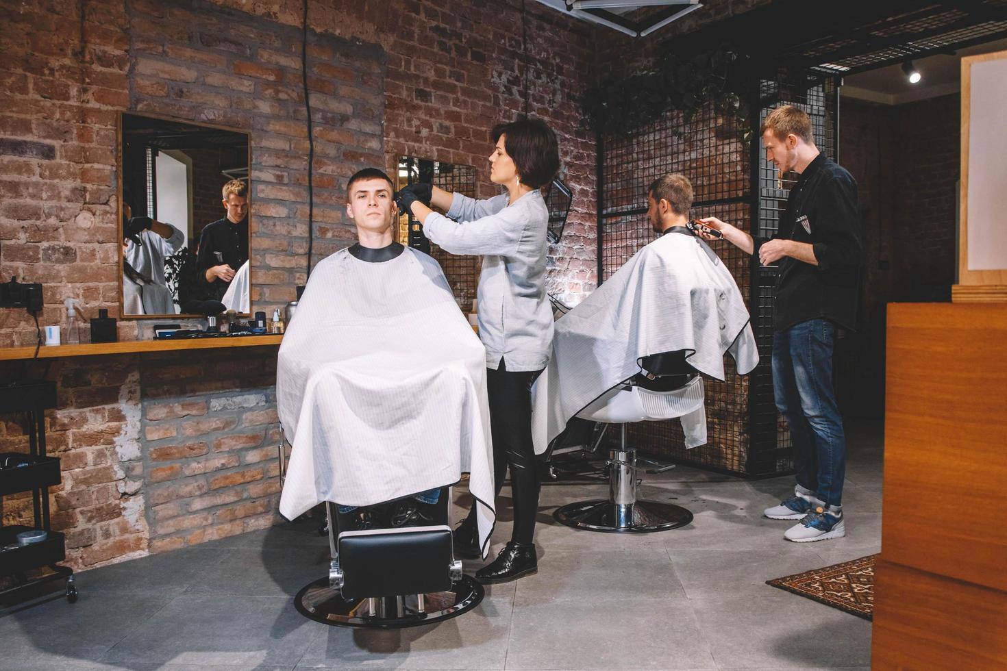 Friseure schneiden ihre Kunden im Friseursalon. Werbe- und Friseurkonzept foto