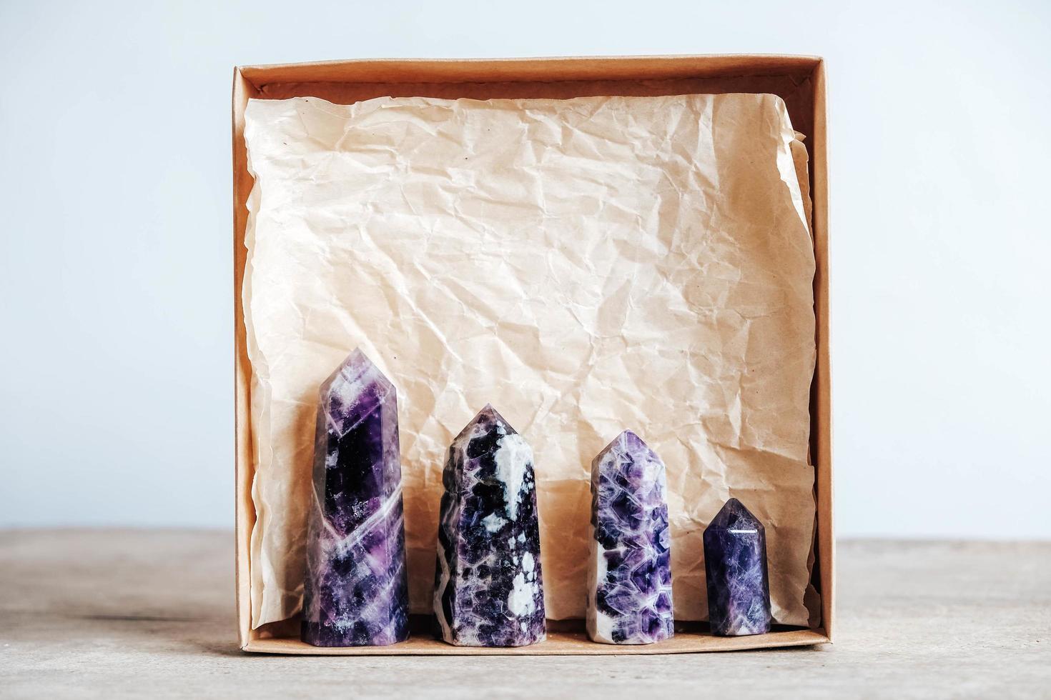 Amethyst polierte Kristallspitze in einer Kraftpapierbox auf Holzuntergrund foto