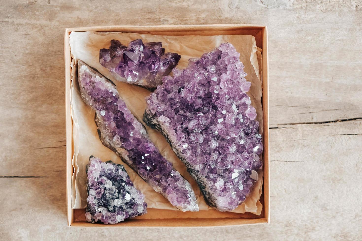 violette Amethystkristalle in einer Kraftpapierbox auf Holzuntergrund foto