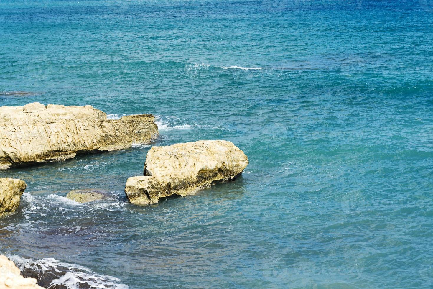 die Wellen brechen an einem steinigen Strand und bilden eine Gischt. Welle und Spritzer am Strand. Wellen, die auf Felsen krachen. foto