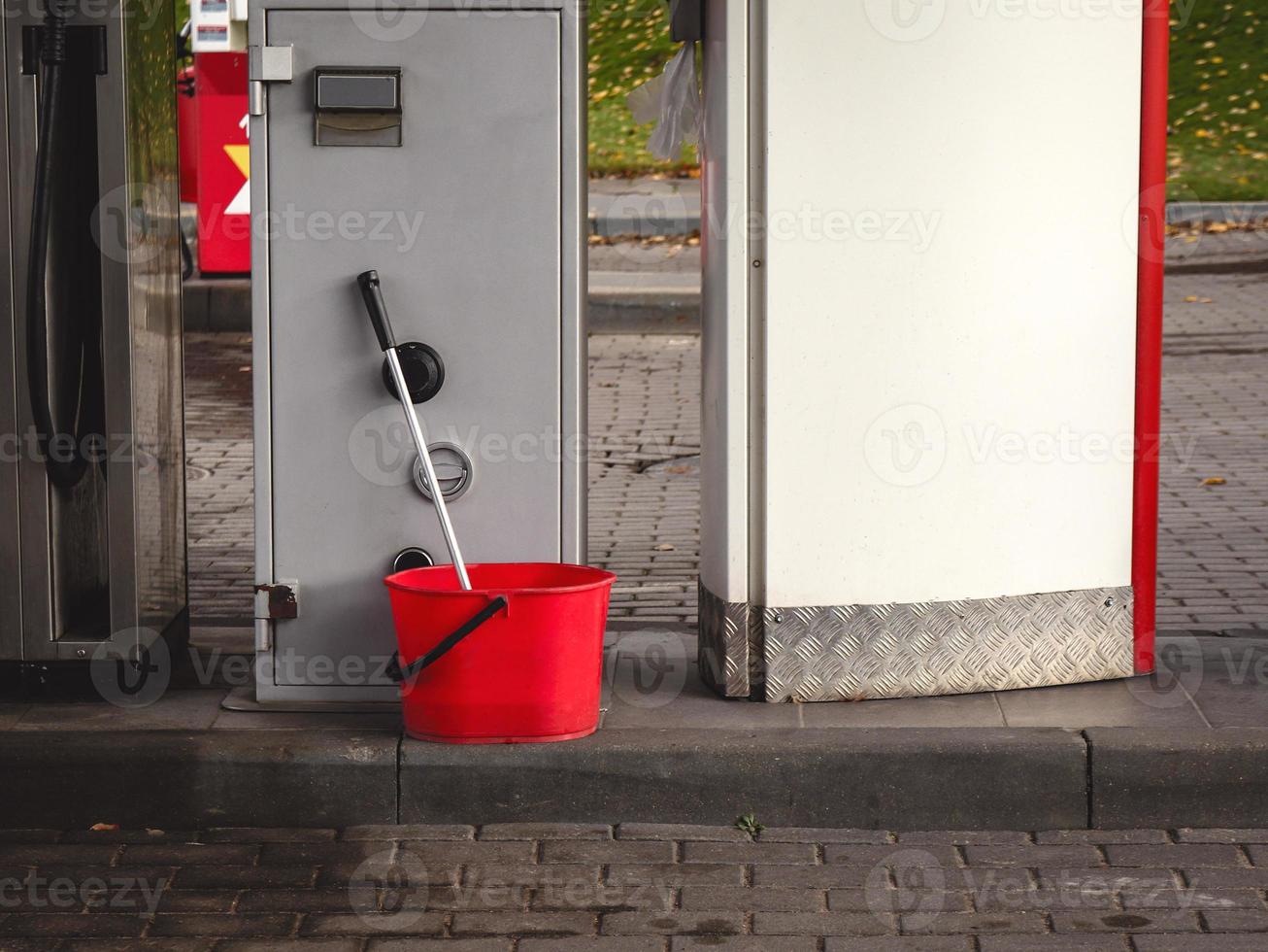 roter Plastikeimer mit Mopp an Tankstelle foto