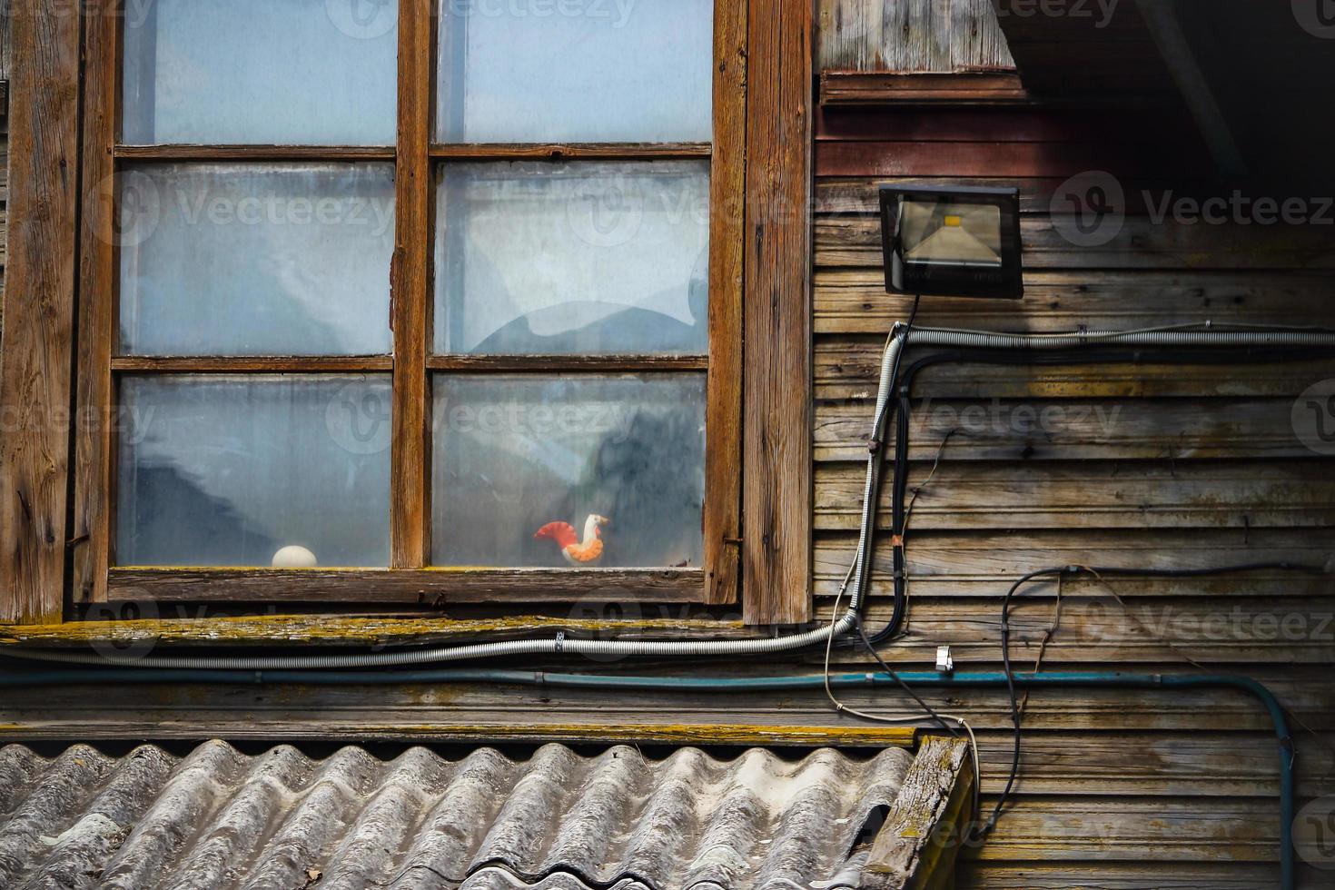 verwittertes Holzrahmenfenster in der Altstadt dunkler Holzplanken-Gebäudewand foto
