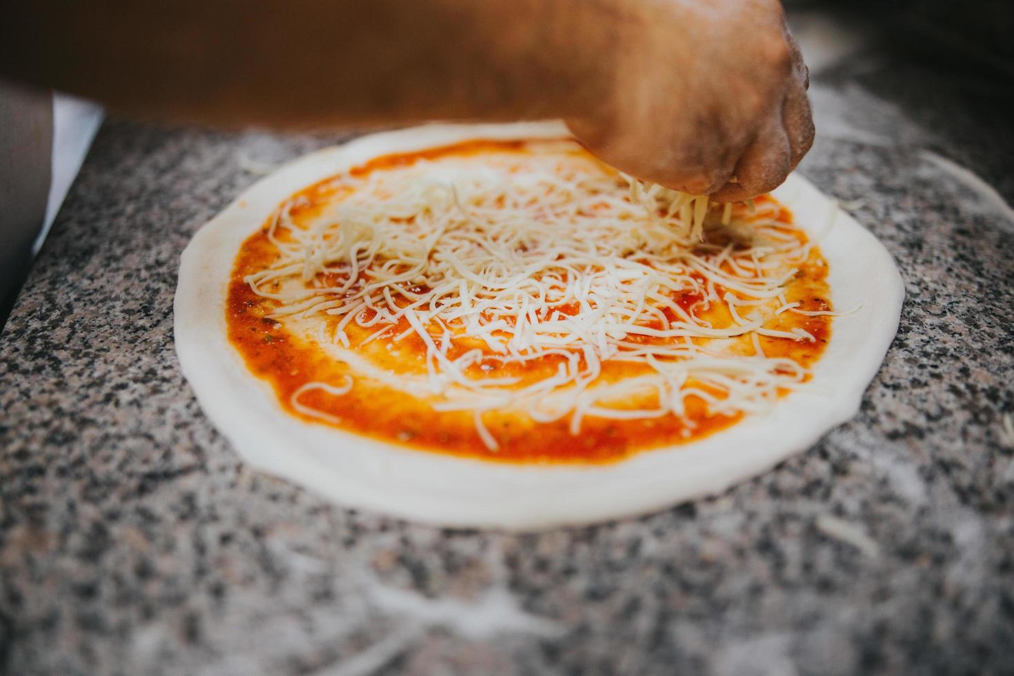 Mann, der Käse auf Pizza legt foto