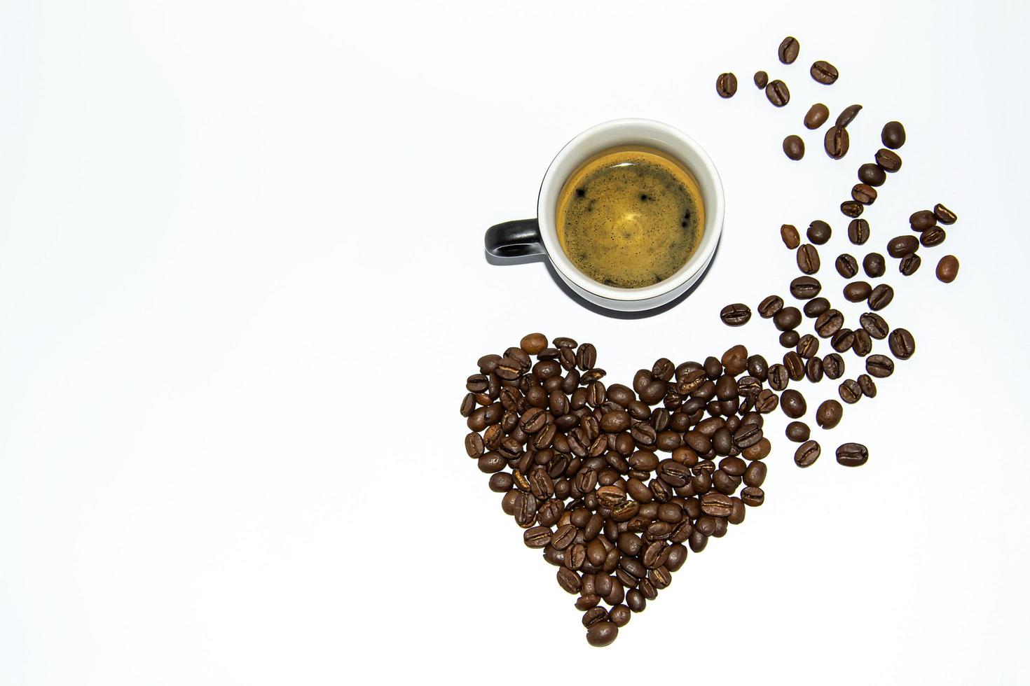 eine Tasse Espresso mit Schaum neben Kaffeebohnen in Form eines Herzens. Lebensstil. deinen eigenen Raum. flach. copispace. foto