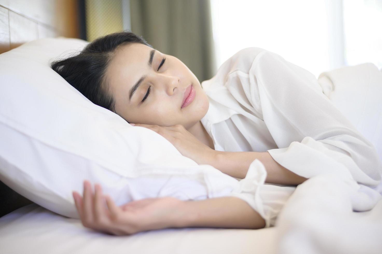 junge schöne Frau, die in ihrem Bett zu Hause schläft foto