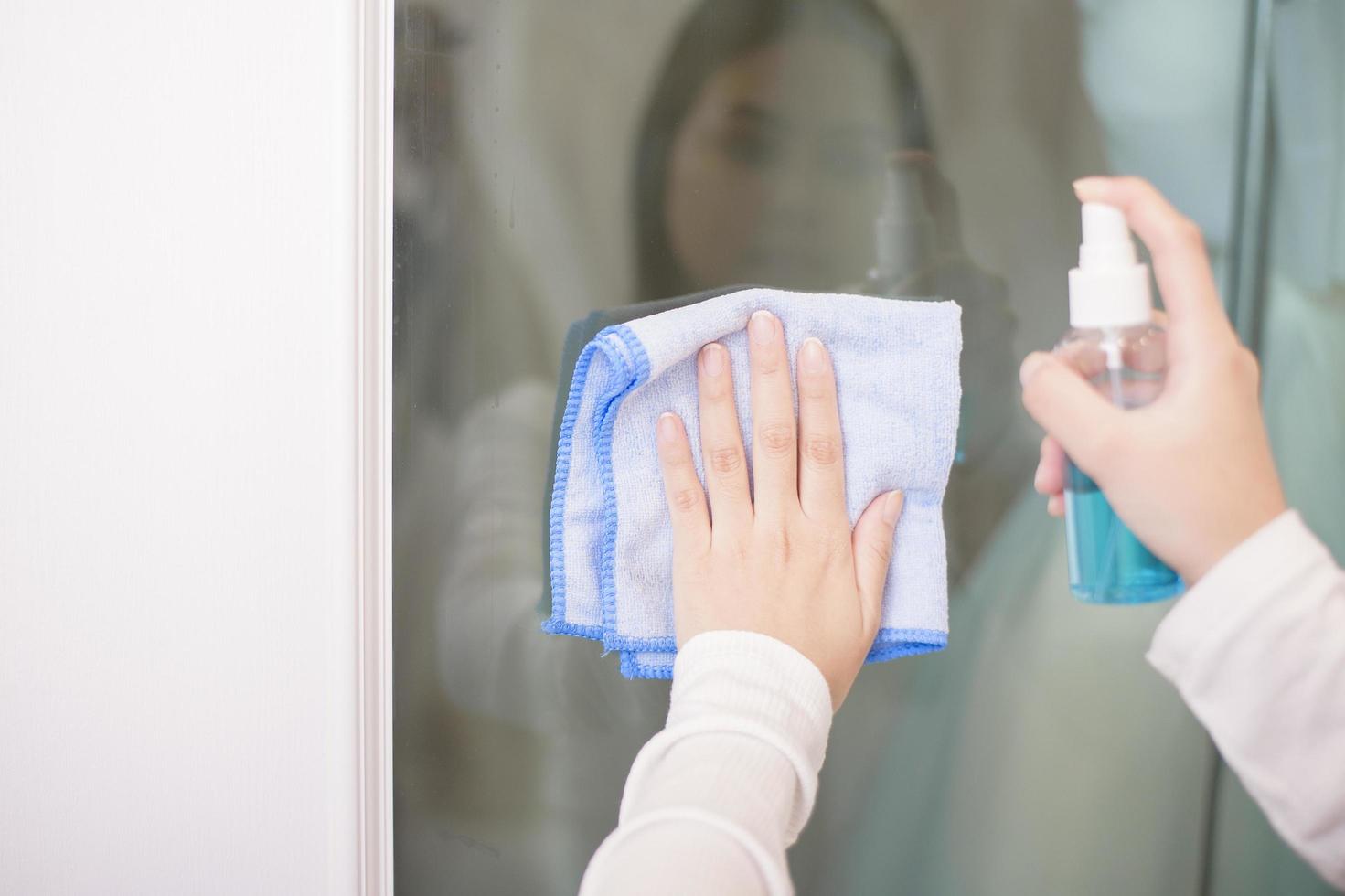 Frau putzt Haus mit Alkoholspray foto