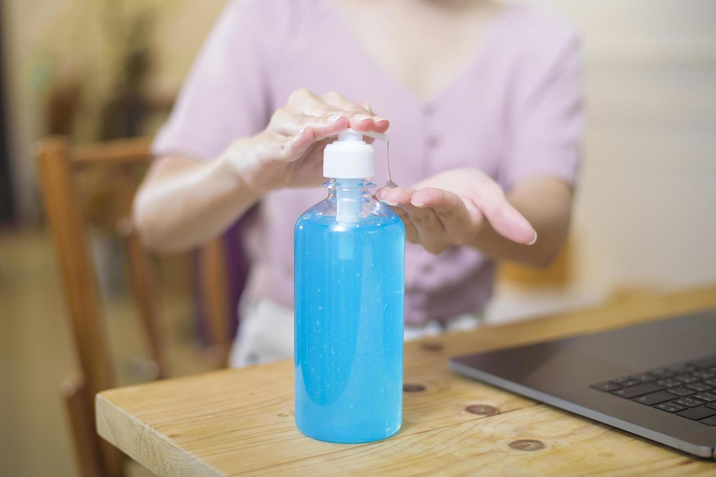 Frau, die von zu Hause aus mit Alkoholgel arbeitet foto