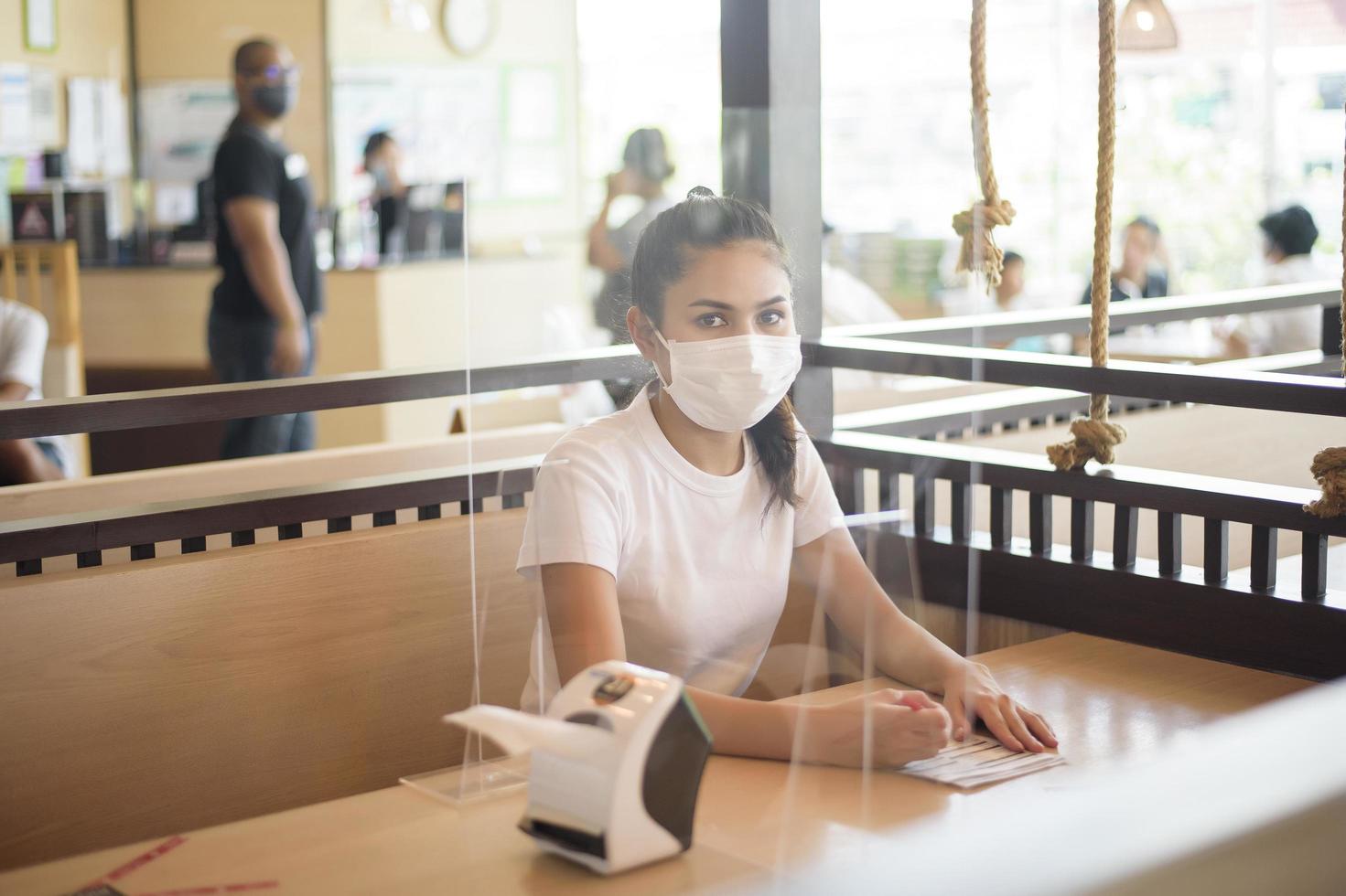 Frau isst im Restaurant mit Protokoll zur sozialen Distanzierung, während sie die Stadt aufgrund einer Coronavirus-Pandemie sperrt foto