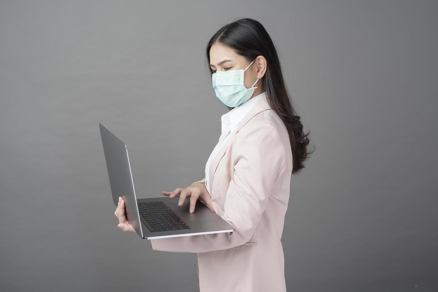 Geschäftsfrau mit Mundschutz hält Laptop-Computer foto