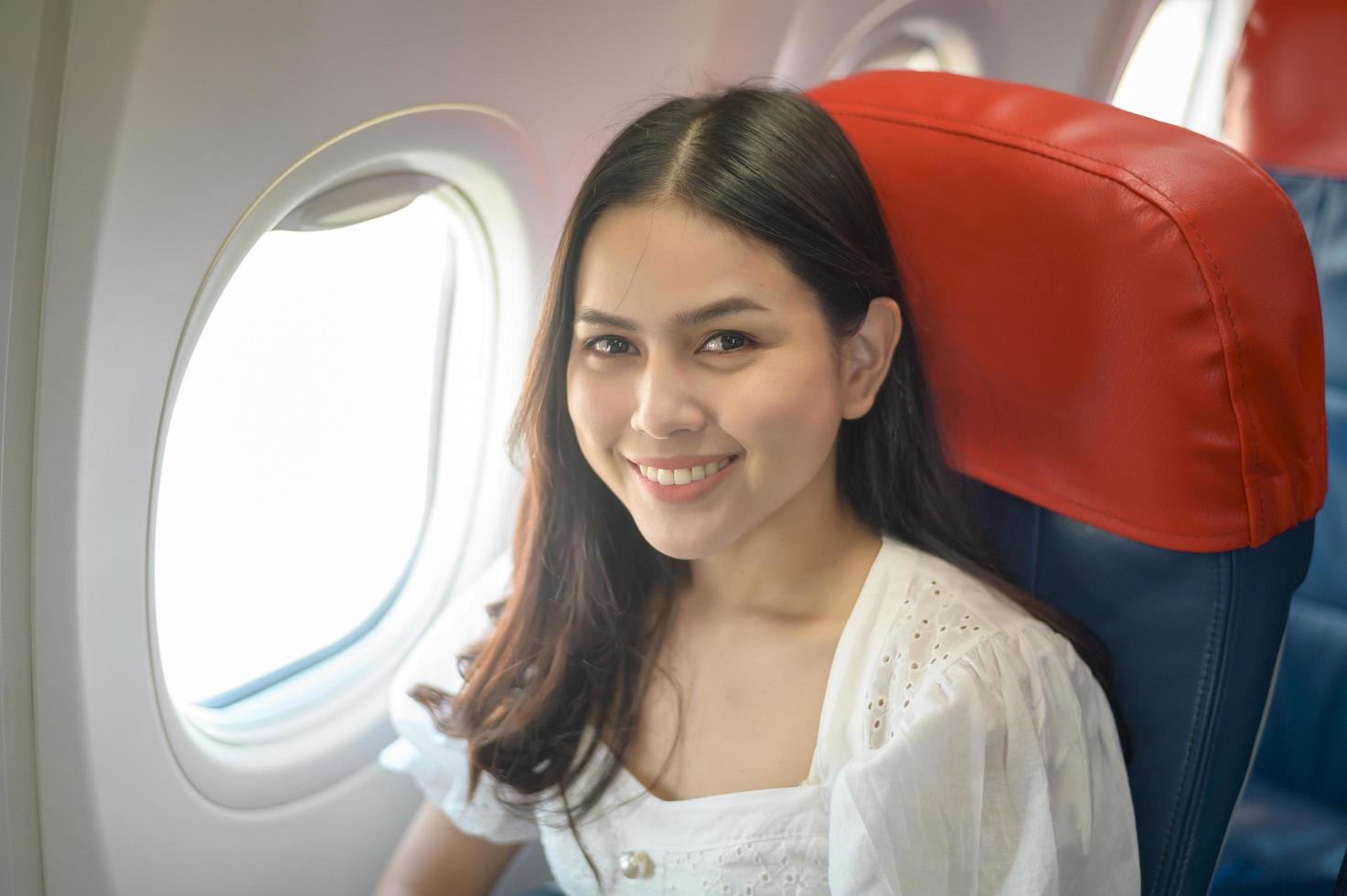 schöne reisende Frau benutzt Smartphone im Flugzeug foto