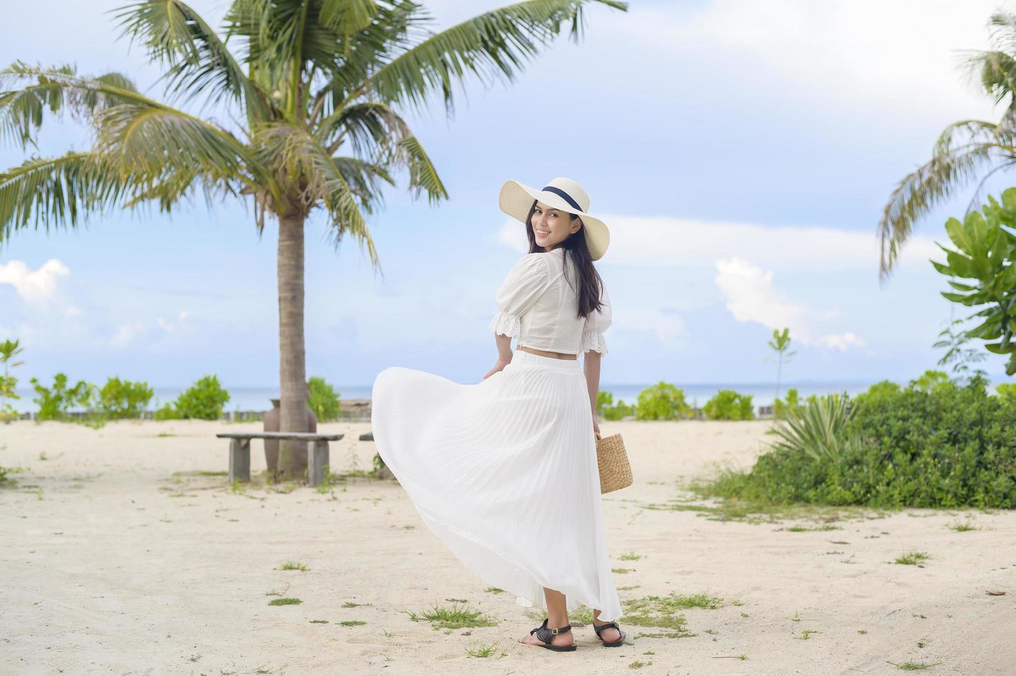 eine glückliche schöne Frau im weißen Kleid, die am Strand, im Sommer und im Ferienkonzept genießt und sich entspannt foto