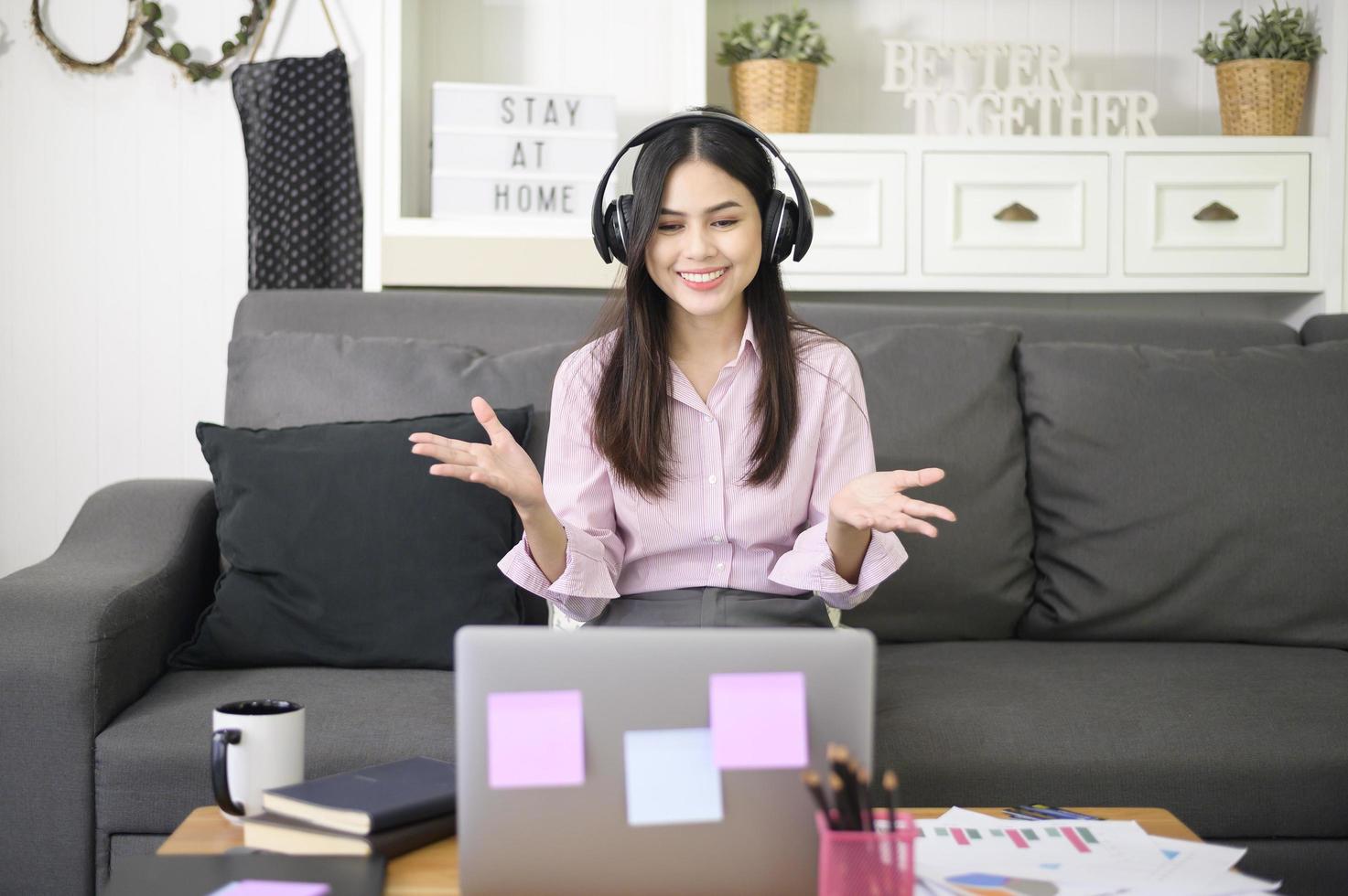 Eine schöne junge Frau, die ein Headset trägt, führt zu Hause eine Videokonferenz über den Computer durch, Geschäftstechnologiekonzept. foto