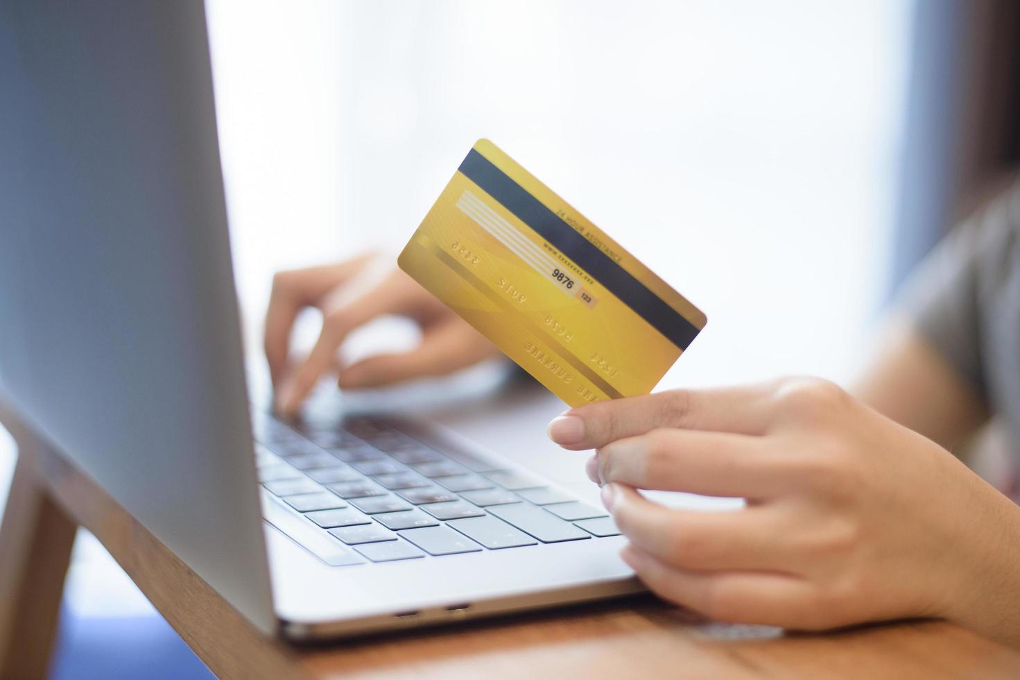 Frauenhand hält Kreditkarte und kauft online ein foto