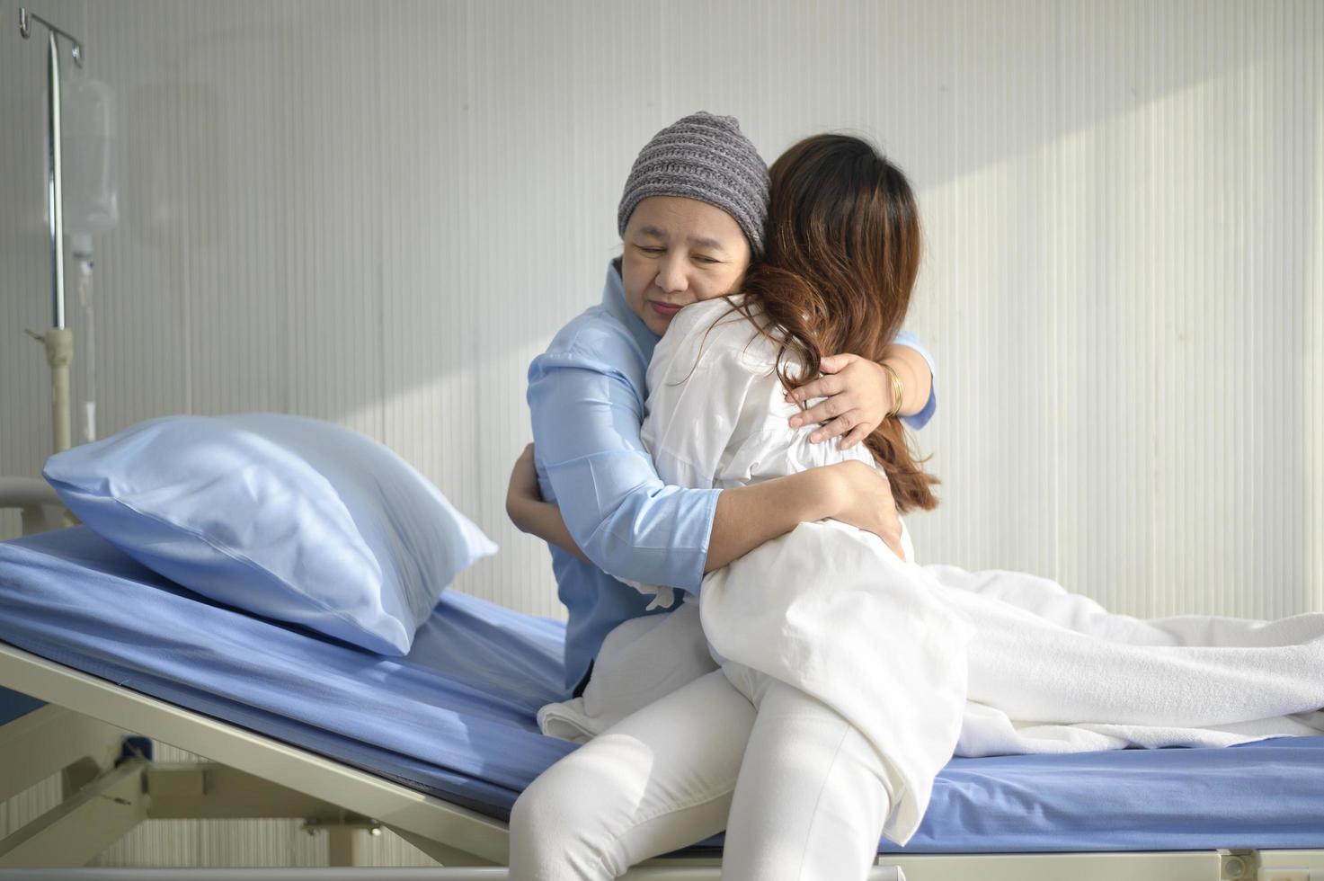 Krebspatientin mit Kopftuch, die ihre unterstützende Tochter drinnen umarmt, Gesundheits- und Versicherungskonzept. foto