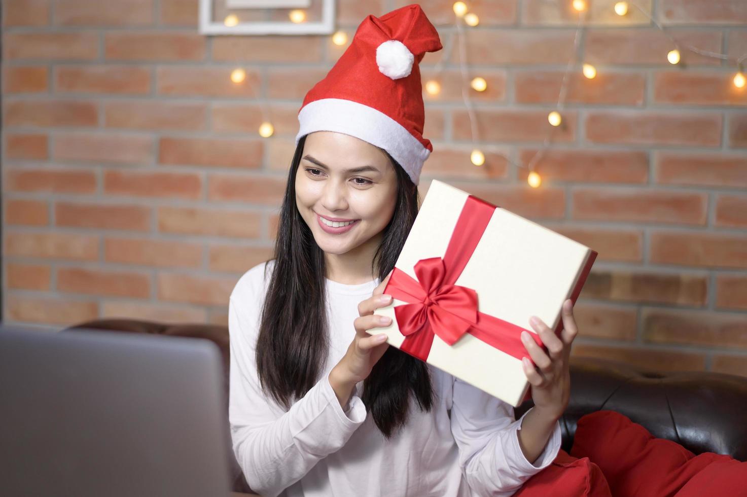 Junge lächelnde Frau mit rotem Weihnachtsmann-Hut macht am Weihnachtstag Videoanrufe im sozialen Netzwerk mit Familie und Freunden. foto