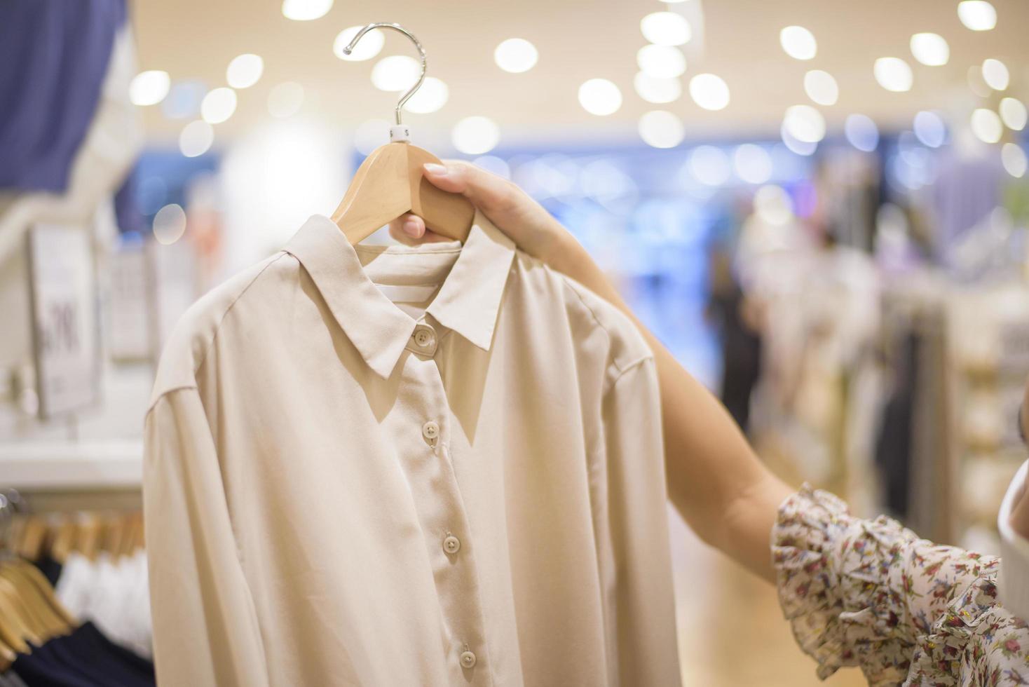 Frau mit Gesichtsmaske kauft Kleidung im Einkaufszentrum foto