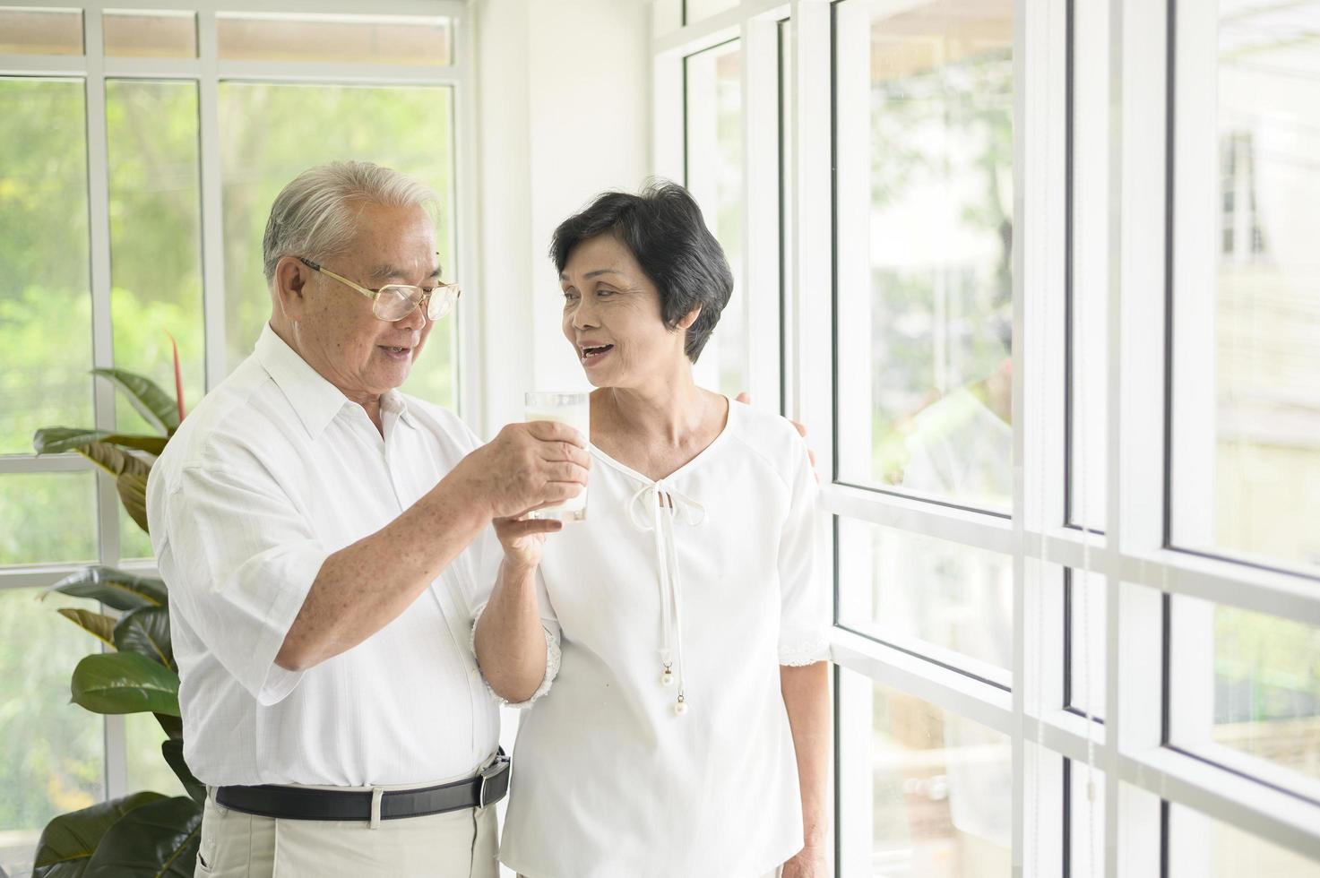 glückliches älteres Ehepaar, das Milch trinkt und Zeit zu Hause miteinander verbringt, Gesundheits- und Ruhestandskonzept foto