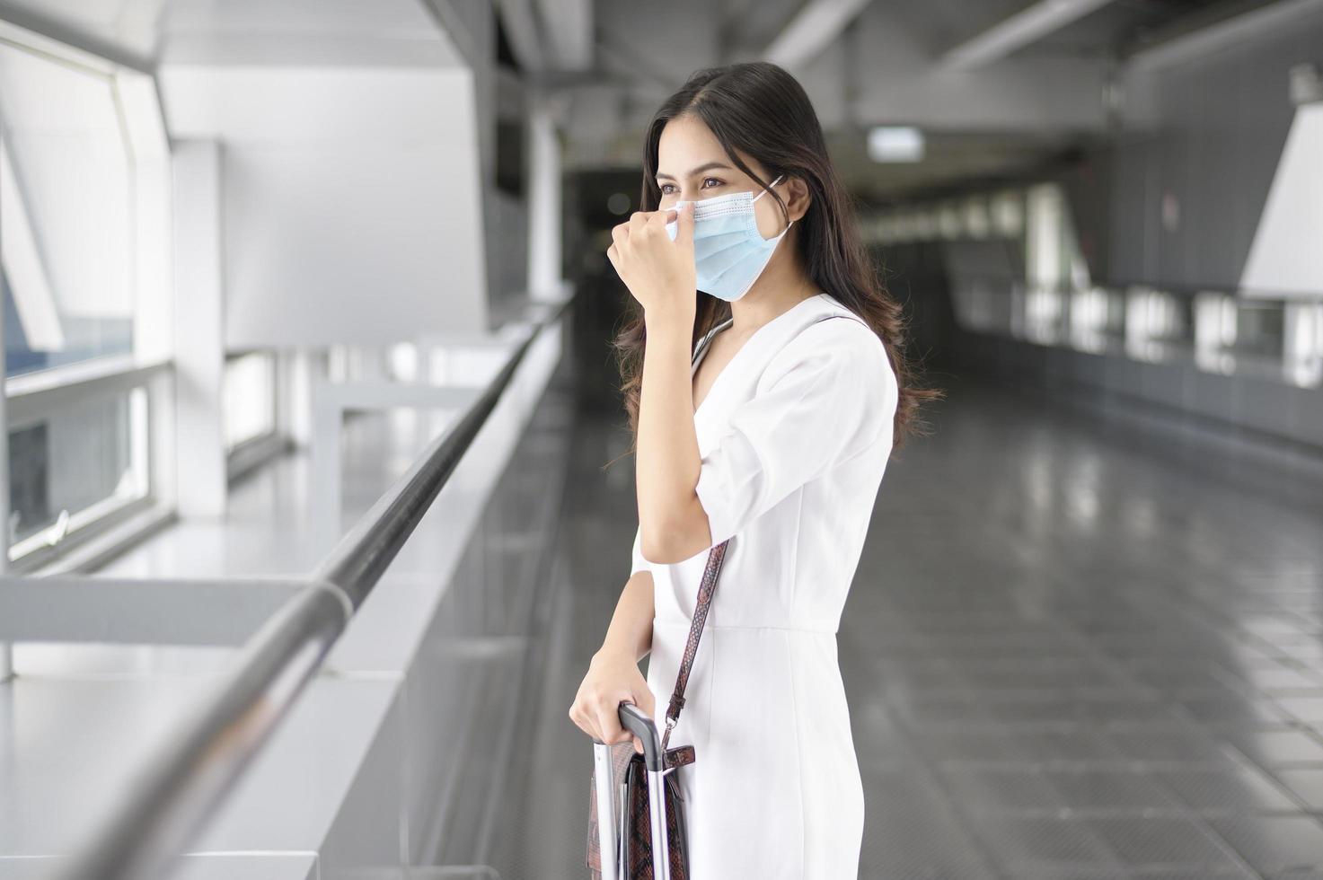 Eine reisende Frau trägt eine Schutzmaske auf dem internationalen Flughafen, reist unter der Covid-19-Pandemie, Sicherheitsreisen, Protokoll zur sozialen Distanzierung, neues normales Reisekonzept foto