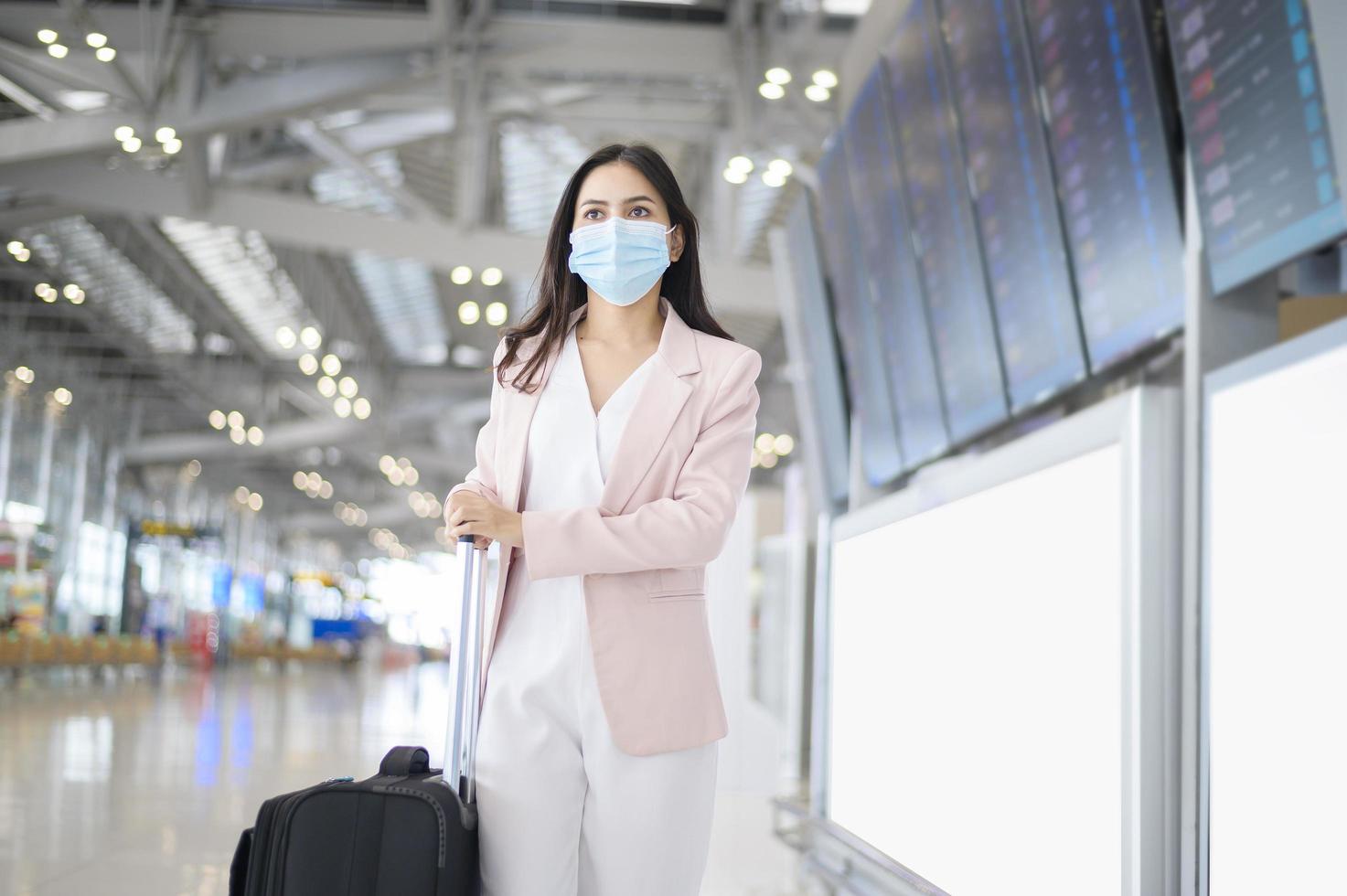 Eine Geschäftsfrau trägt eine Schutzmaske auf dem internationalen Flughafen, reist unter der Covid-19-Pandemie, Sicherheitsreisen, Protokoll zur sozialen Distanzierung, neues normales Reisekonzept foto