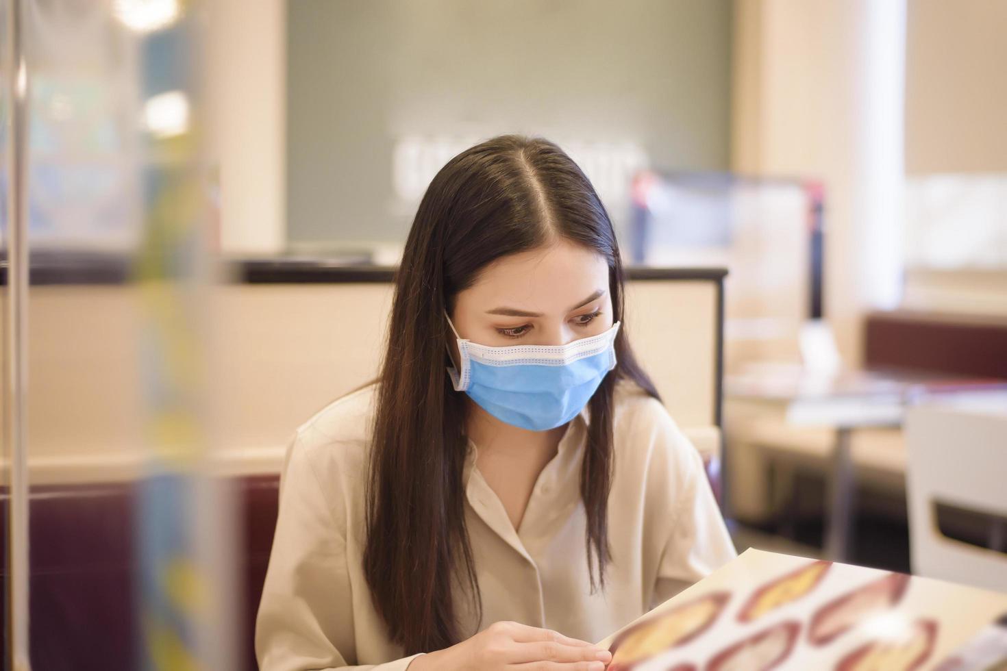 Frau isst im Restaurant mit Protokoll zur sozialen Distanzierung, während sie die Stadt aufgrund einer Coronavirus-Pandemie sperrt foto