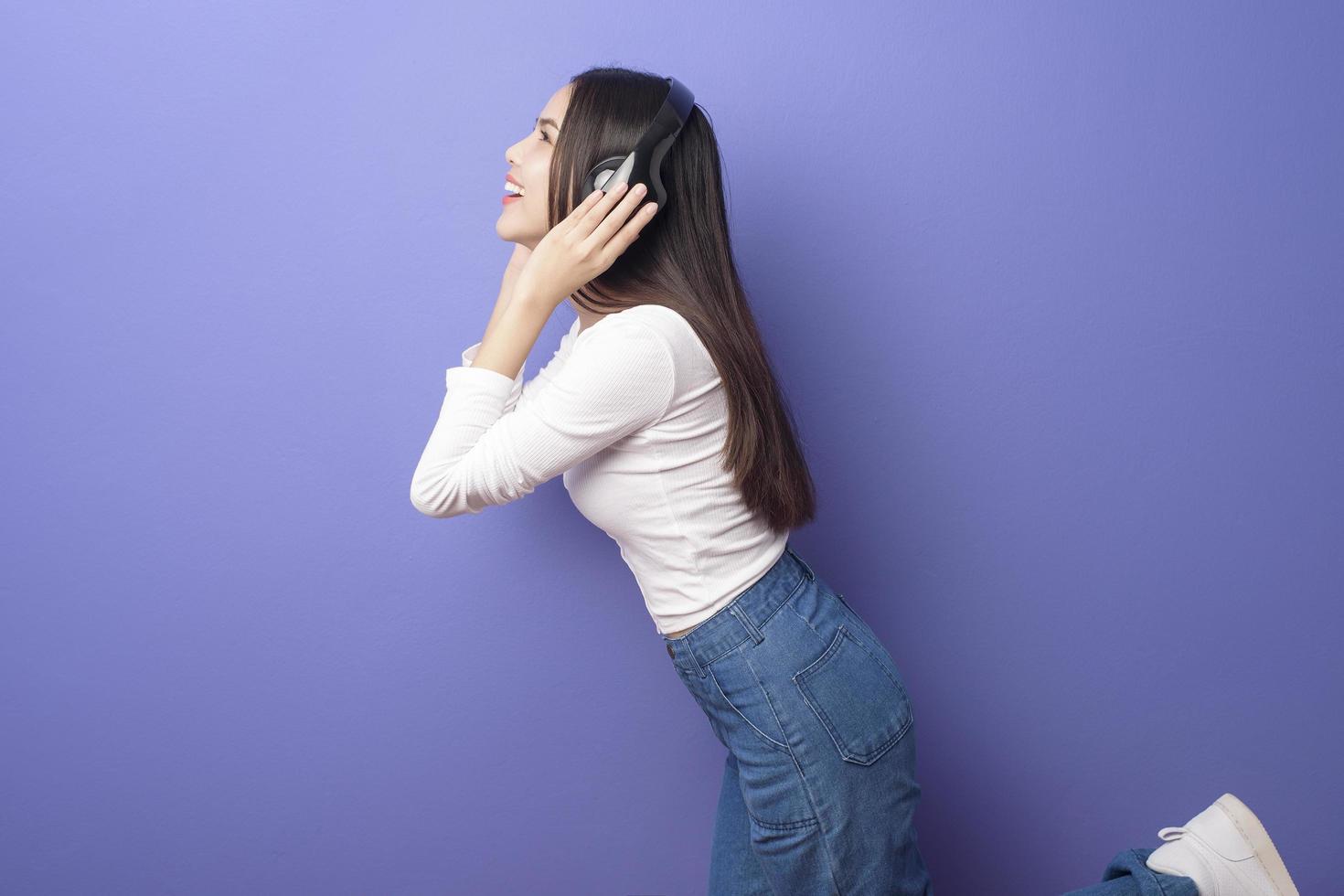 junge Frau hört Musik auf lila Hintergrund foto