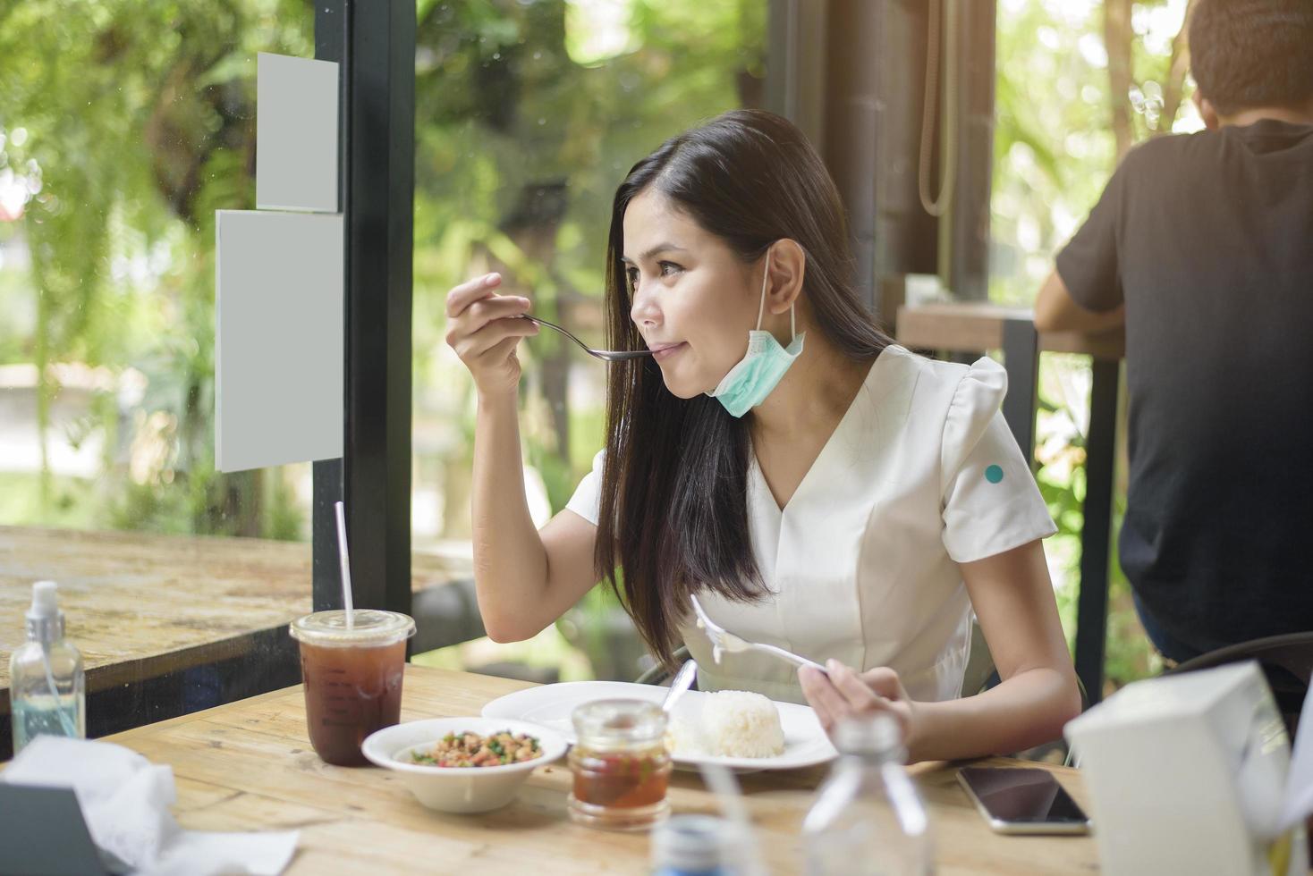 junge frau mit gesichtsmaske isst im restaurant, neues normales konzept. foto